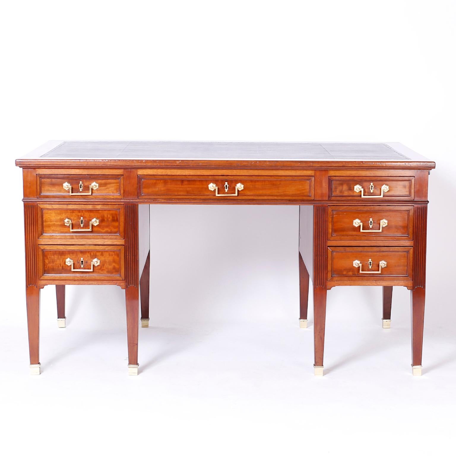19th century English mahogany seven drawer desk featuring a tooled brown leather top, two leather top pull out trays, handmade construction, brass hardware, finished back, and an elegant classic form.

Kneehole width: 23