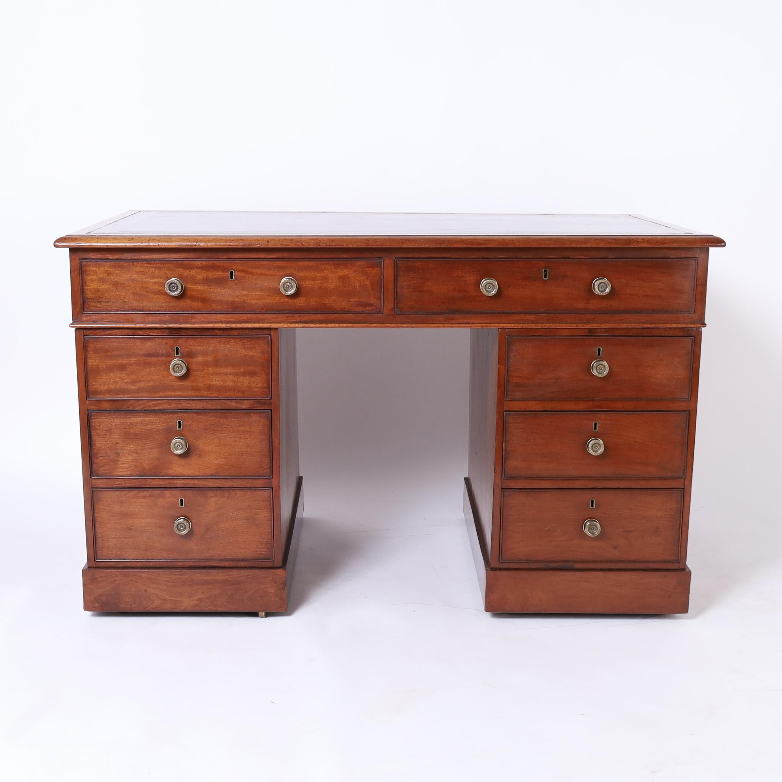 Hermoso escritorio inglés del siglo XIX hecho a mano en caoba con la tapa original de cuero labrado sobre una forma de doble pedestal con ocho cajones en el frente, herrajes de latón y patas de bloque montadas sobre ruedas insertadas.

Altura de las