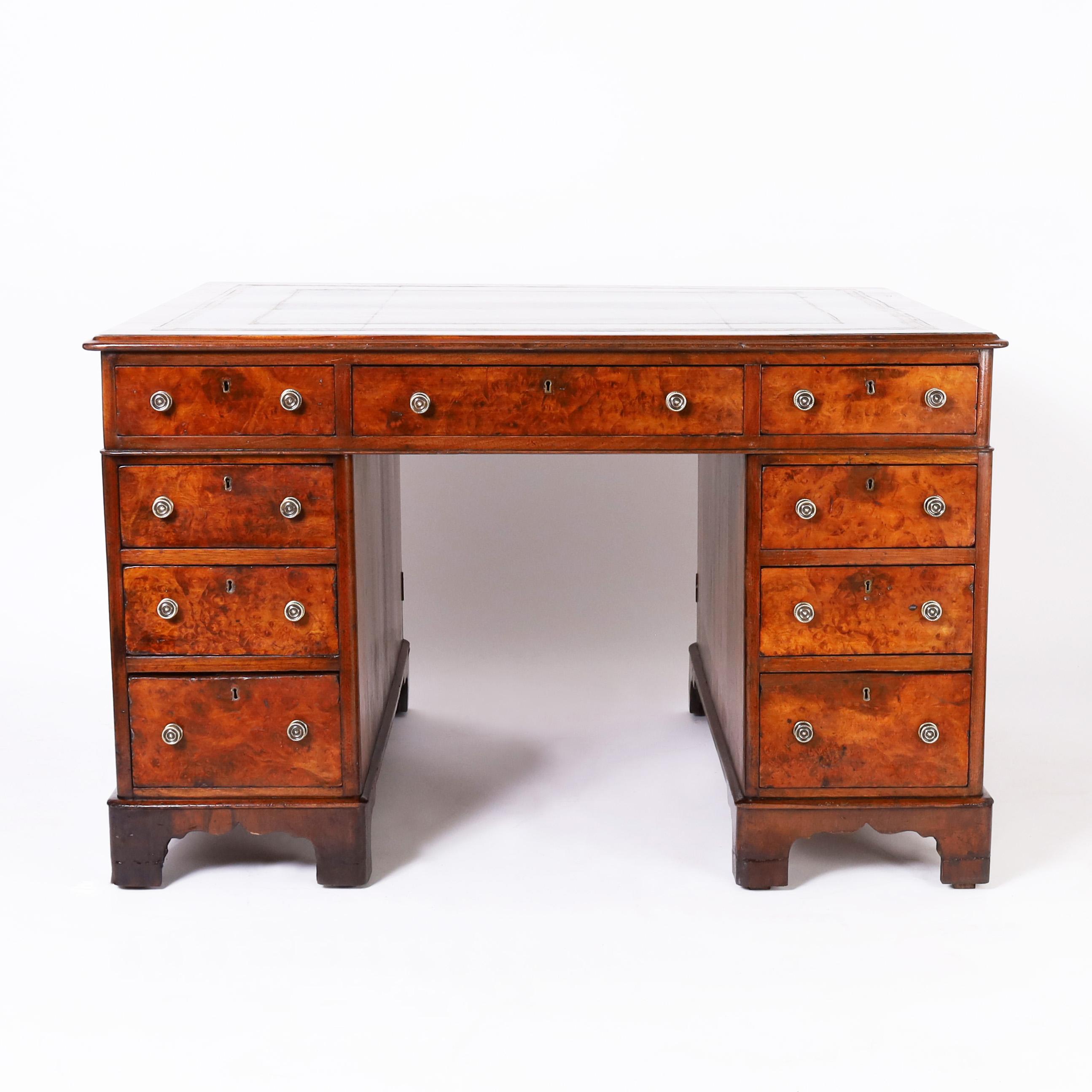 Handsome 19th century English partners desk crafted in mahogany in three-piece construction, featuring the original tooled leather top, African Bubinga wood drawer and door fronts, brass hardware and bracket feet.