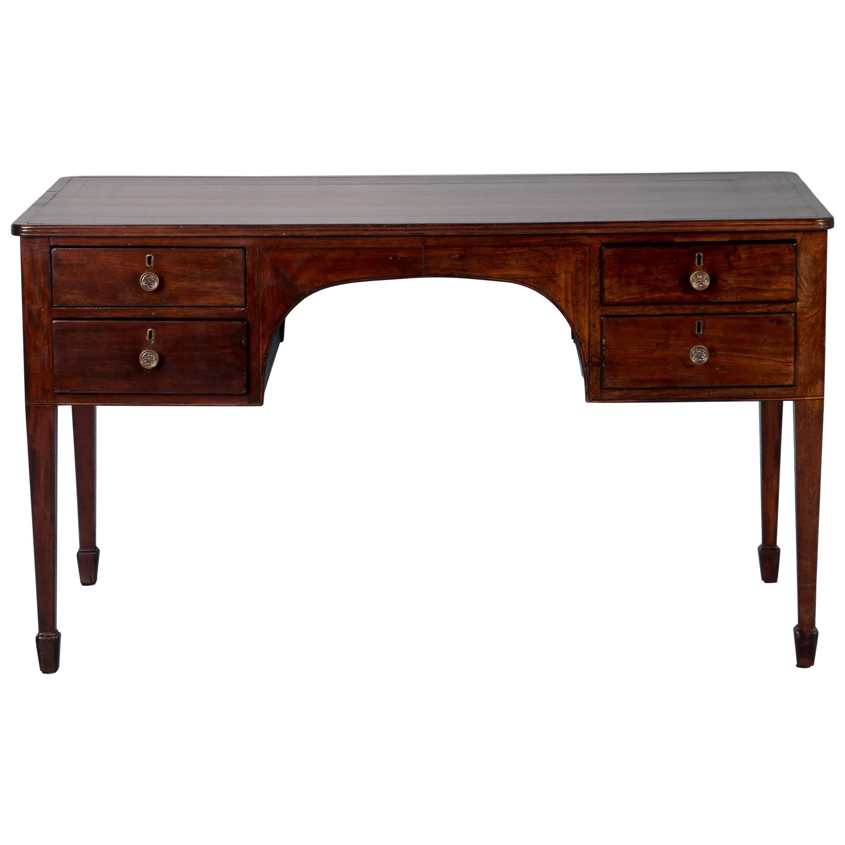 The solid dark mahogany glows on this antique desk from England that features the original time worn green leather top with a hand tooled gold border. There are four working drawers on one side and four imitation drawers on the other with the