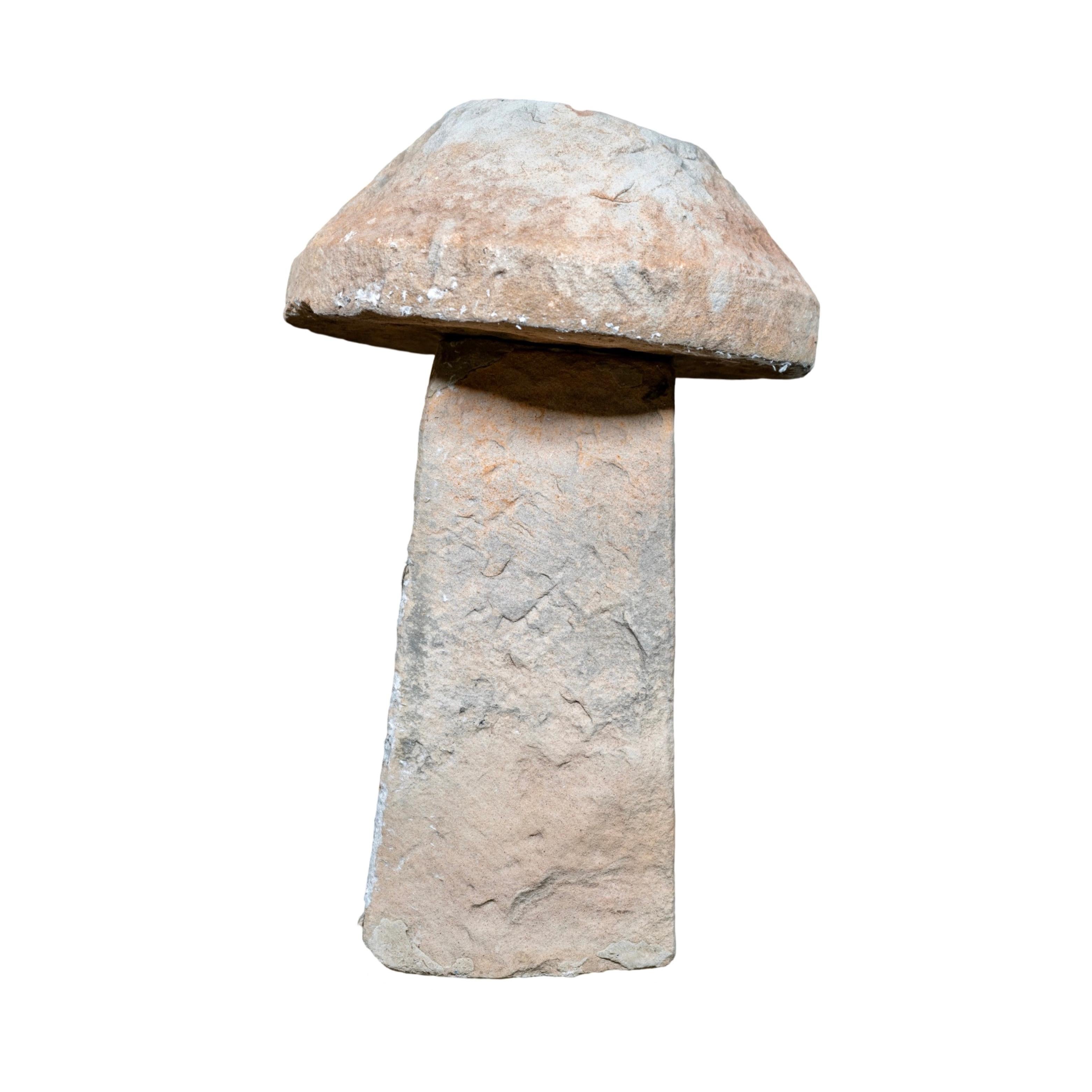 An 18th-century staddle stone crafted from limestone and originating from England, this piece consists of two separate components: the base and the cap. When stacked together, they form a complete staddle stone. Traditionally, staddle stones served