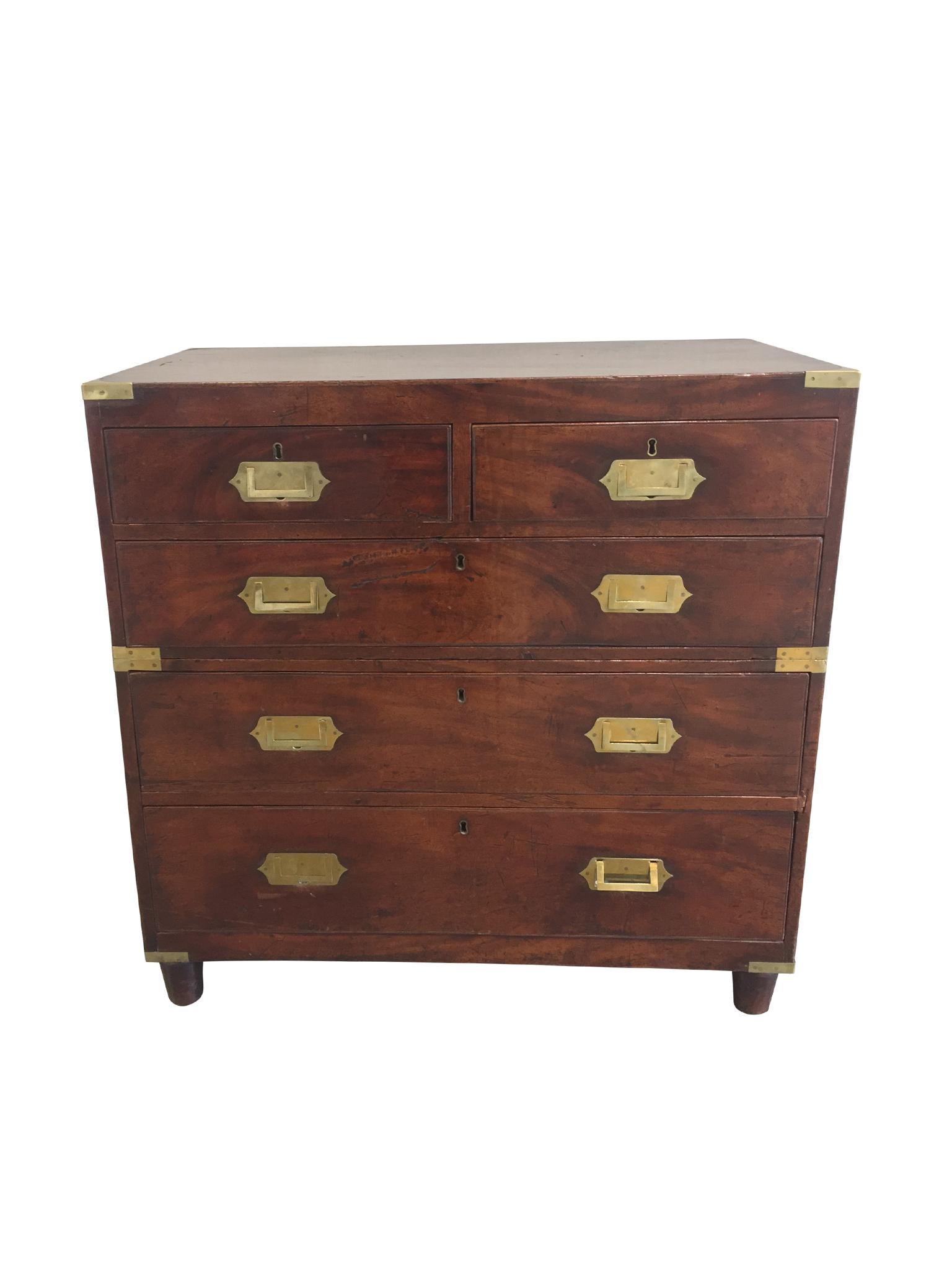 An antique English campaign chest of drawers, 19th century. This well-aged chest consists of two case pieces that elegantly stack and lock together. The wood is a honey-brown mahogany hue with visible dents and scratches that have rounded over the