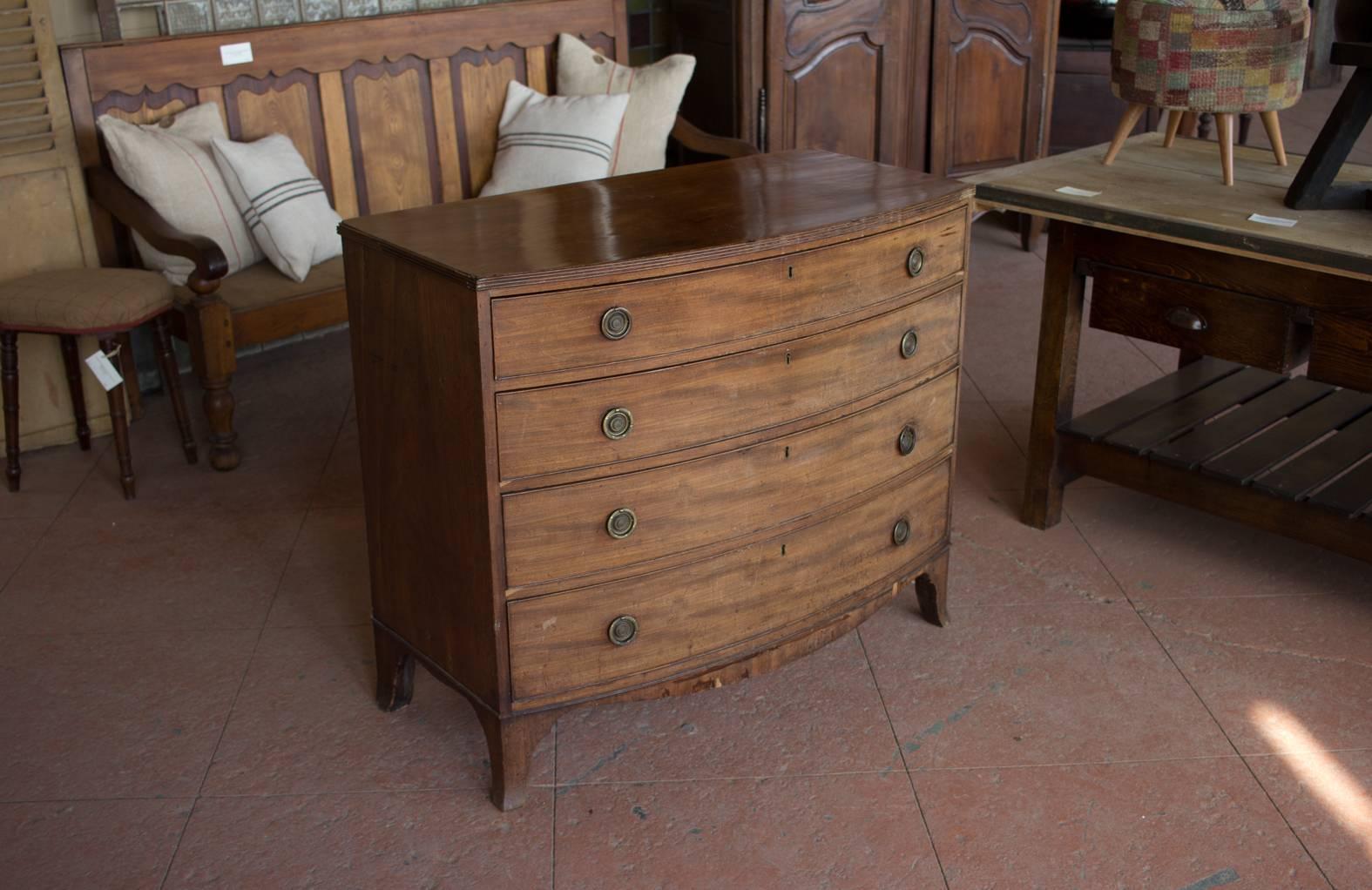 Antique mahogany bow front chest of drawers with a fitted top drawer over three graduated drawers with brass ring handles.