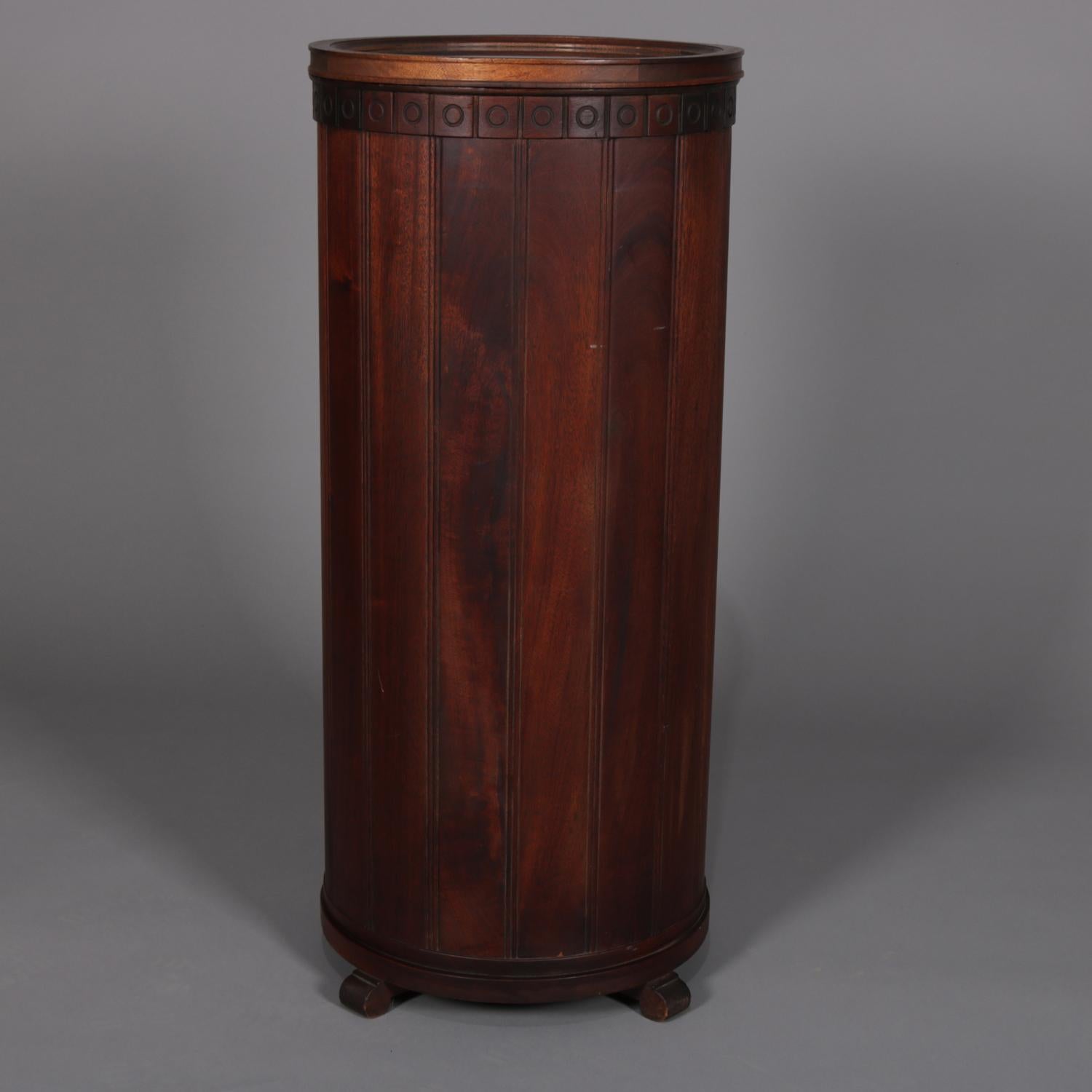 An antique English cellarette and display pedestal features mahogany construction in column-form with Greek key bordering, concealed door opens to reveal interior storage for liquor, bottles and barware, raised on scroll form feet, removable glass