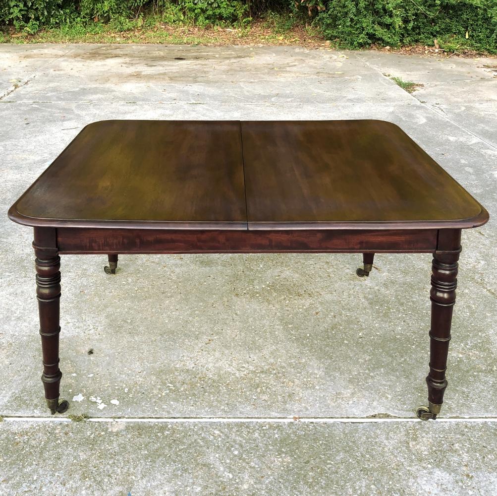 Antique English mahogany dining table with leaf features tailored lines and the richness of the natural beauty of the exotic imported mahogany to create the perfect dining surface. Sides slide out to create space for a single large leaf, as depicted