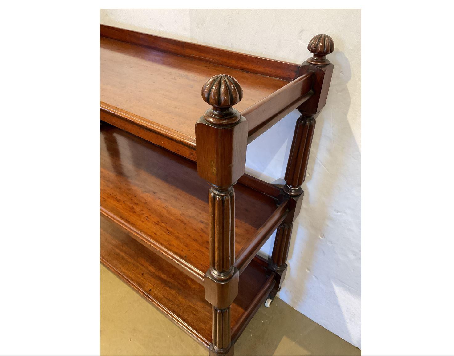 This is a beautiful classic style English dumbwaiter! The rich colored mahogany wood is completed by carved design on the sides and ornamental knobs on the top corners. The server has three roomy shelves and is set on wheels which makes it