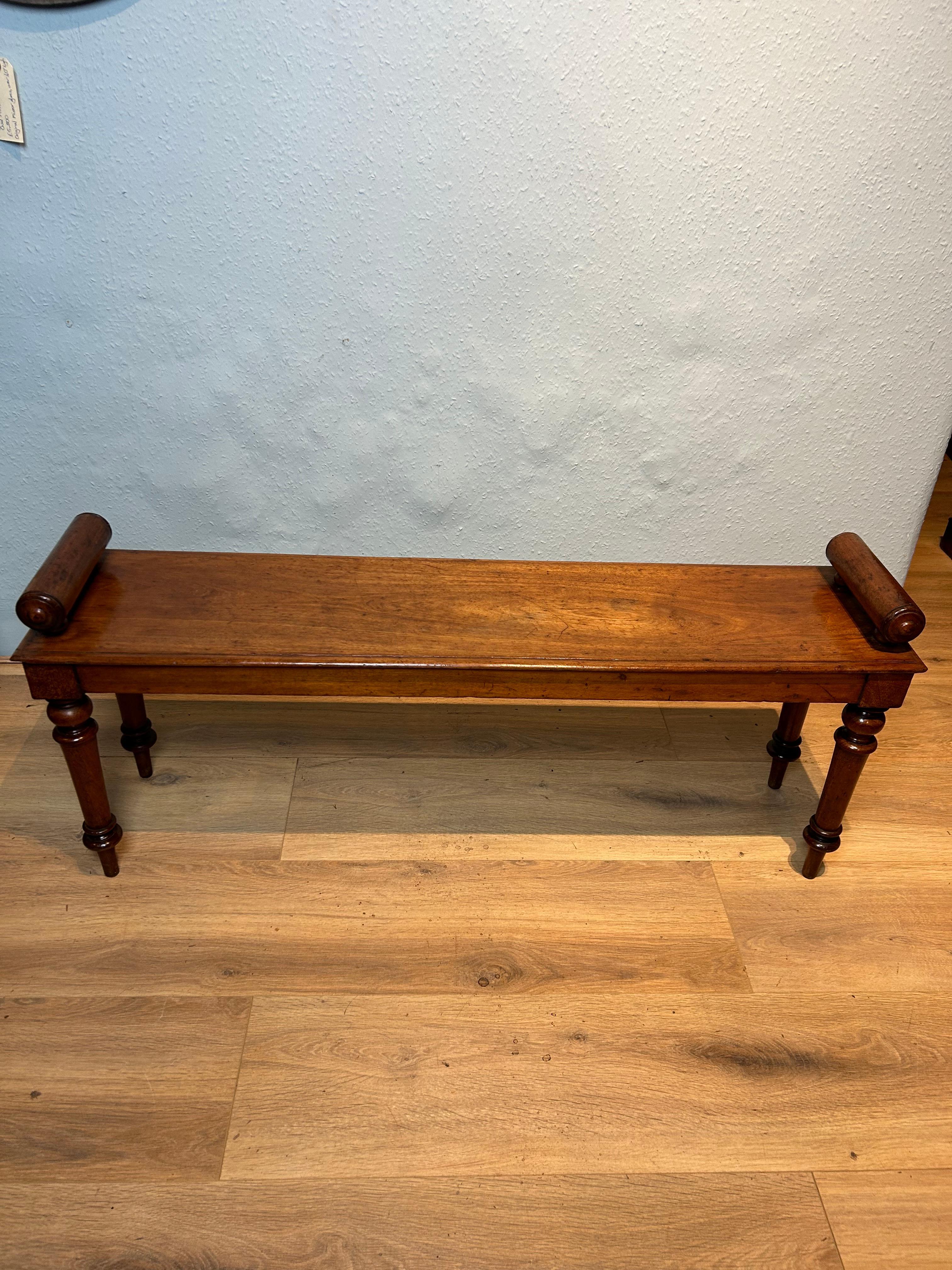 19th century mahogany hall bench circa 1850 with bold turned raised bolster ends resting on a light honey coloured thumb moulded seAt, seating on elegant finely tuned legs, retaining original patina,the underside is supported with a central rail