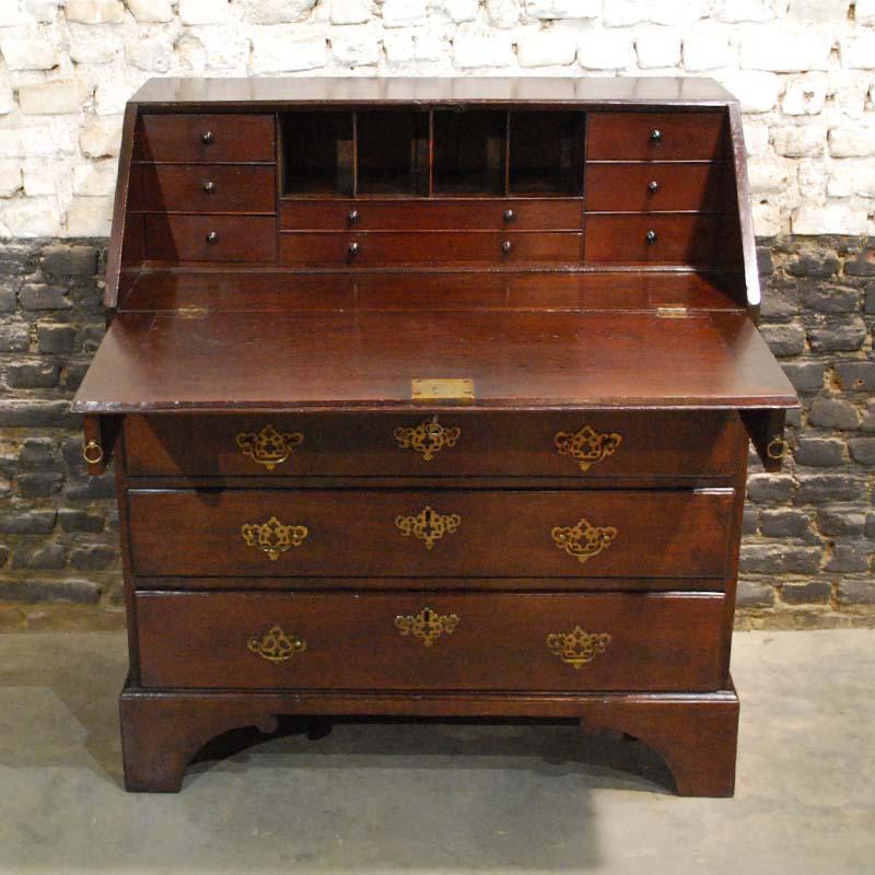 This beautiful slant front desk was made in England in the early 19th century. 
It is made in solid mahogany with beautiful grain. It stands on bracket feet with four drawers fitted with the original bat-wing period swing grip handles with solid