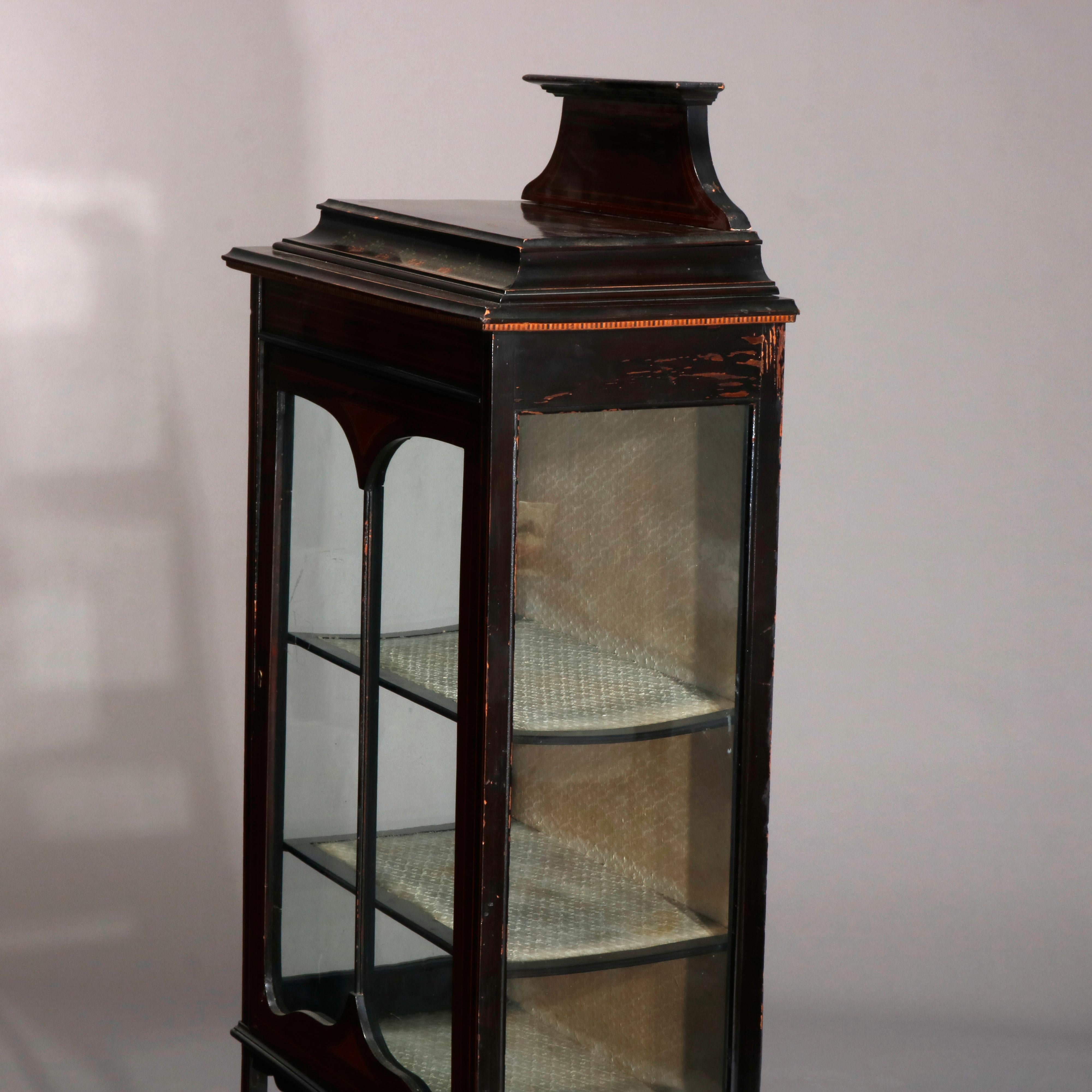 An antique English mahogany petite curio vitrine offers mahogany construction in stylized pagoda form with shaped crest surmounting satinwood inlaid and banded single door case having shaped apron and raised on splayed banded legs, circa