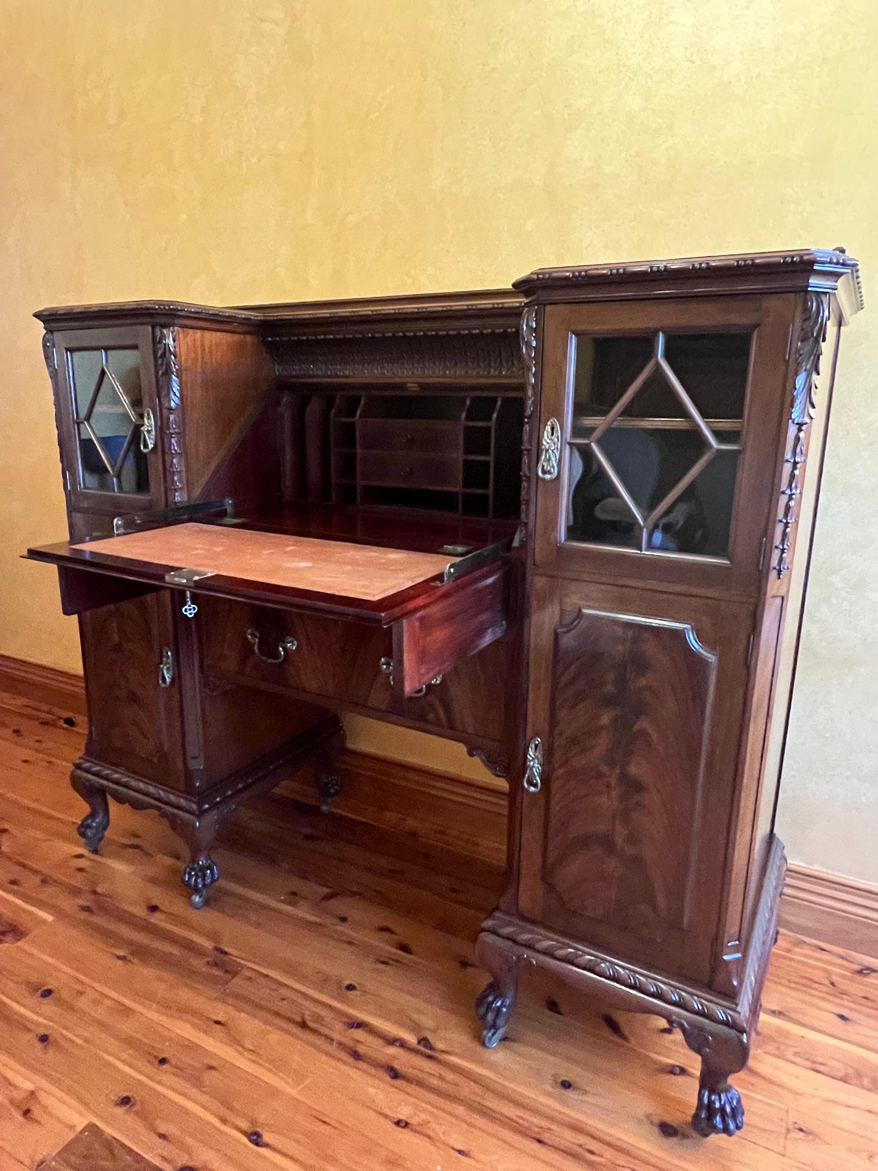 Prince of Wales feather carved detail, flame mahogany, drop front writing bureau comes with key, four external china or display cabinets, three external drawers, fourteen pigeon holes, two trinket drawers, terracotta leather tooled writing area,