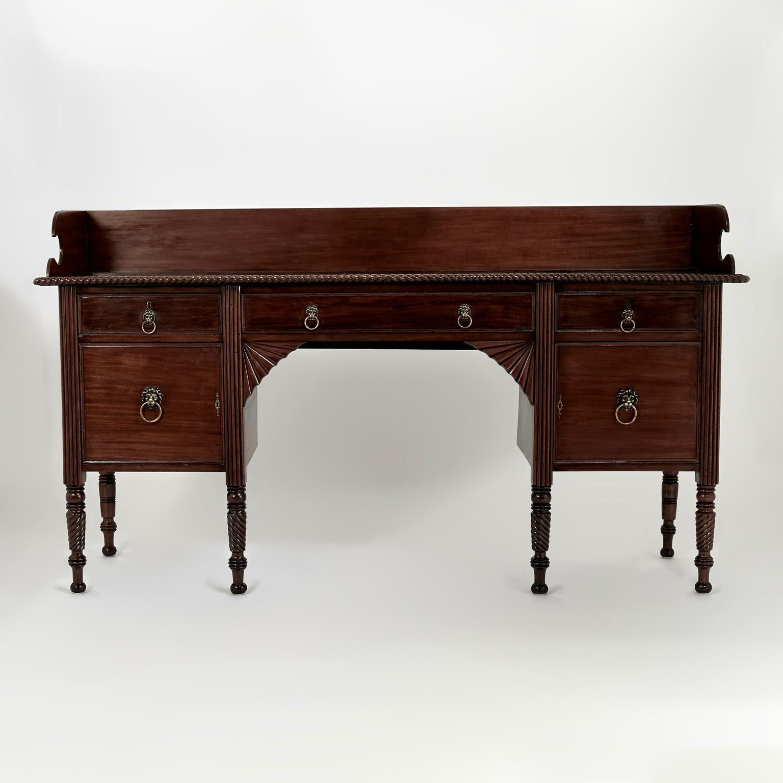 Splendida credenza inglese del XIX secolo realizzata a mano in mogano con una galleria intorno al piano con scanalature e bordi intagliati a corda ritorta su una cassa con tre cassetti e due ante con tiretti in ottone a testa di leone, supporti