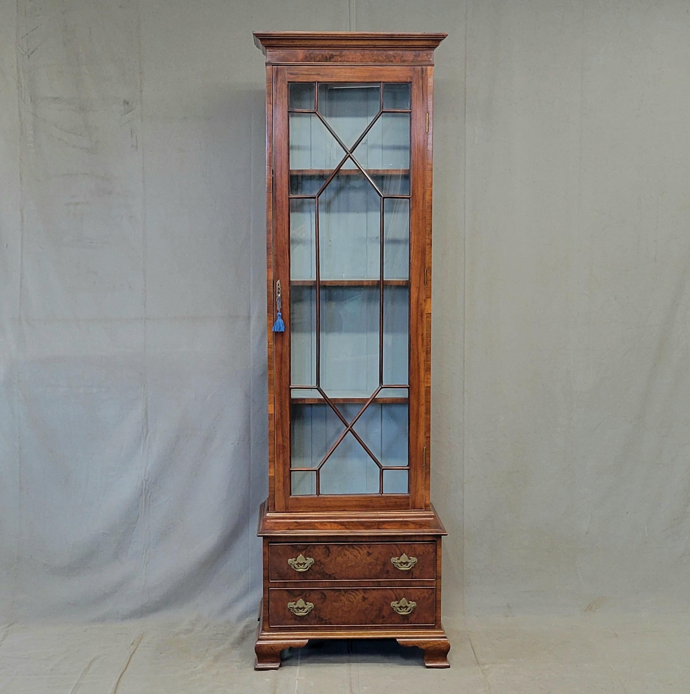 Un bellissimo mobile da esposizione in mogano inglese a due pezzi, dalle proporzioni eleganti. La porta a vetri è divisa artisticamente con montanti a rombi e vetri originali. Il ripiano centrale è fisso, mentre i ripiani superiore e inferiore sono
