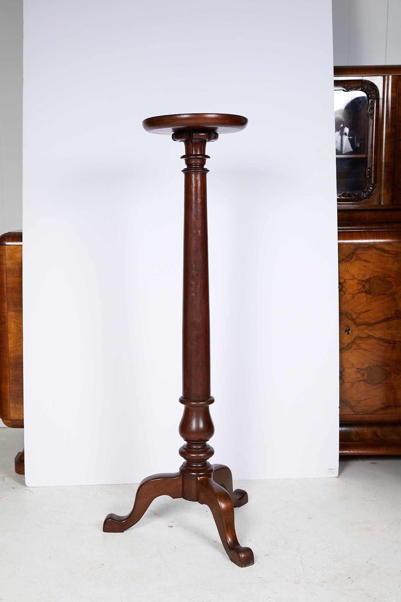 Early 20th century English Georgian style mahogany torchere or plant stand with a molded dish top supported by a tall carved and turned tapering column, raised on three shaped cabriole legs. 

The stand measures 52.75