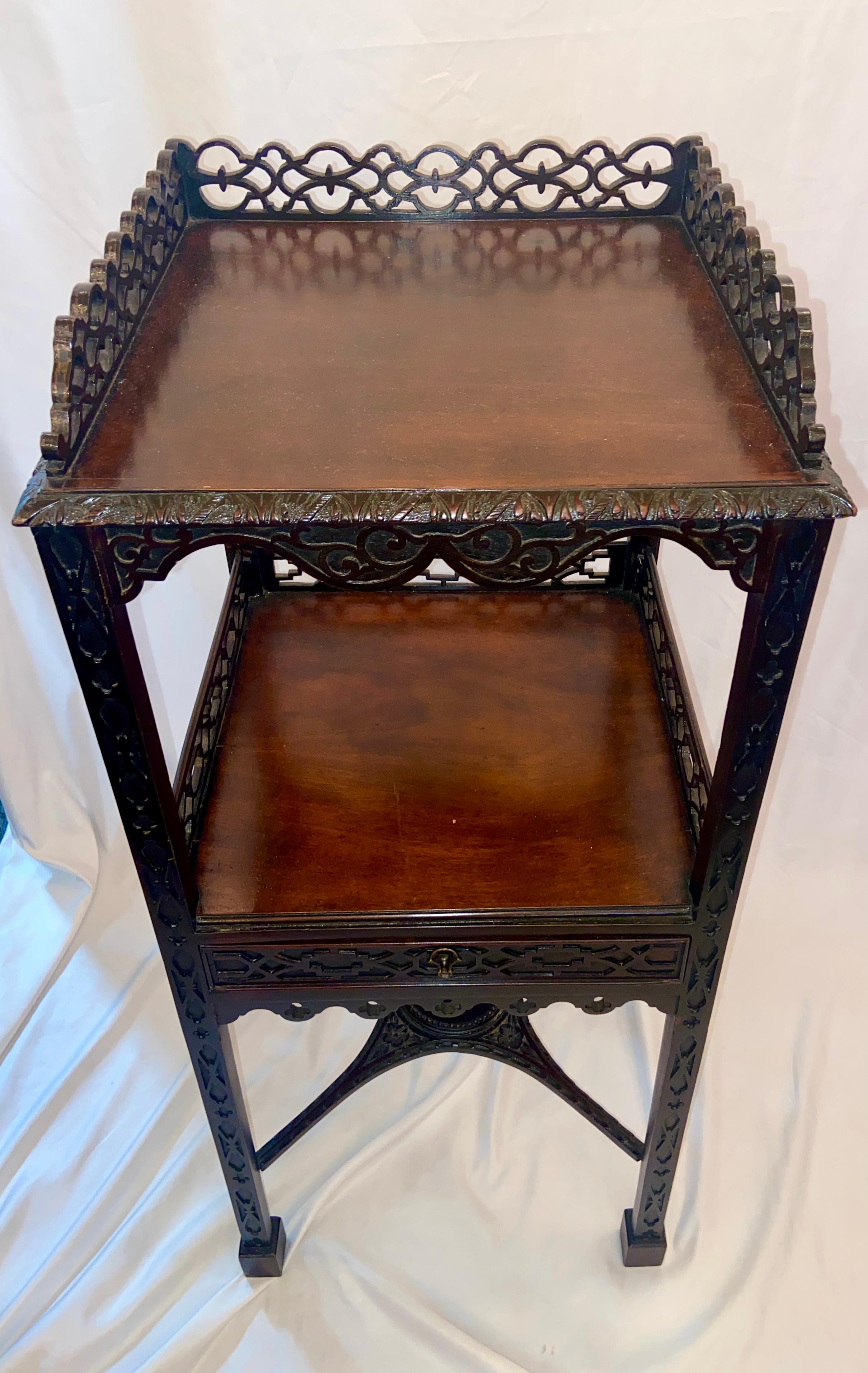 Antique English mahogany two-tier Chippendale tea table with intricate fretwork, Circa 1880.
Final photo shows the table in one of our display windows, at far right with a pretty peacock lamp on top.
