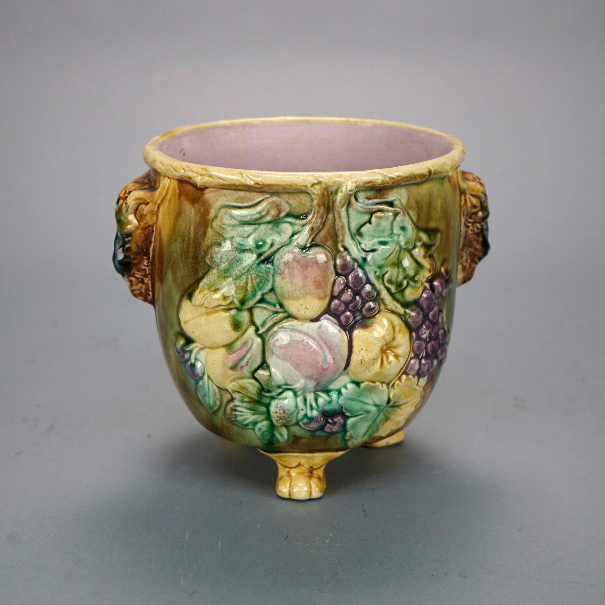 An antique English Majolica jardiniere offers pottery construction with double rams head handles on vessel having fruit and leaf design in relief and raised on foot form legs, 19th century

Measures- 8.25''H x 9.25''W x 8''D
