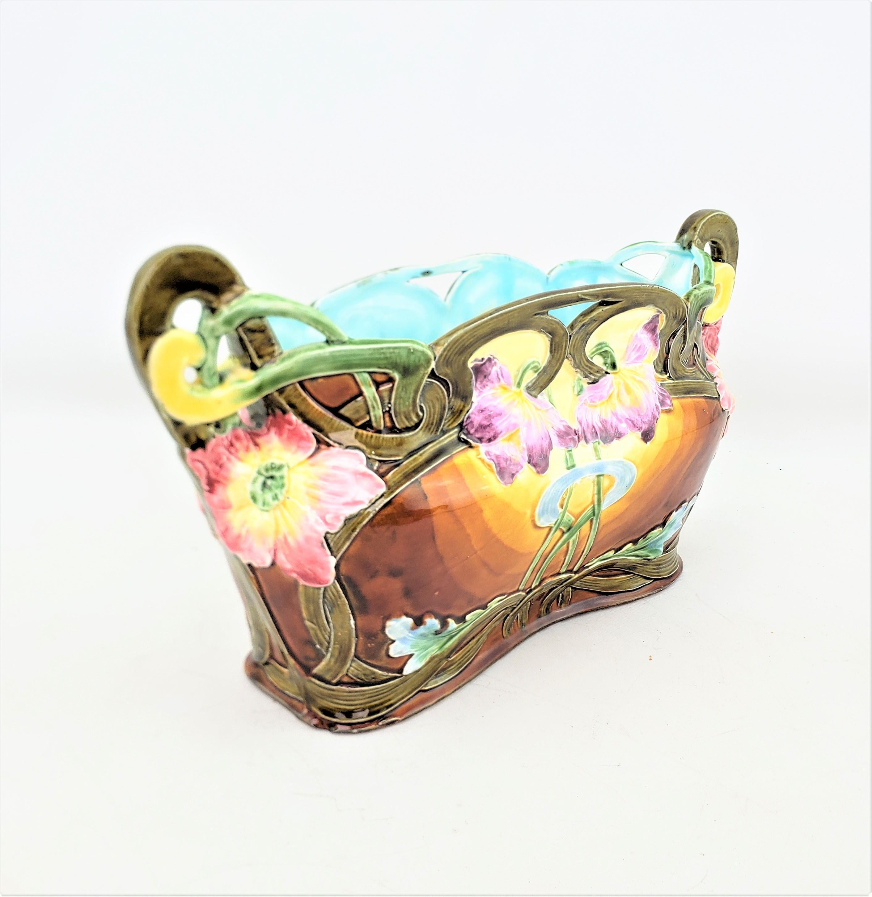 This antique planter is unsigned, but presumed to have originated from England and date to approximately 1890 and done in the period Art Nouveau style. The planter is composed of Majolica and done in a figural flower basket shape with vibrant floral
