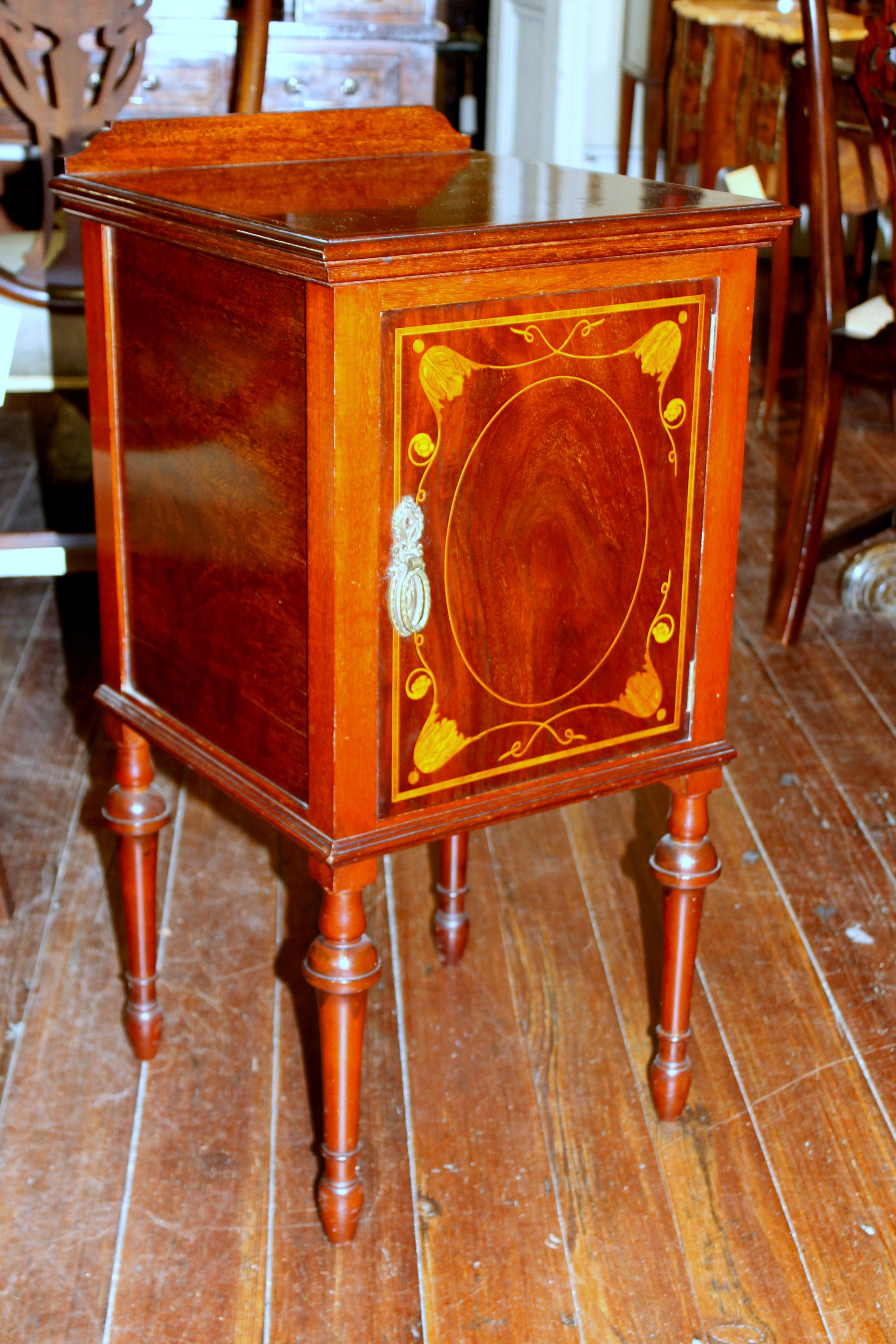 Superb antique English marquetry inlaid mahogany bedside/ chair-side cabinet.

Please note handsome tulip wood narrow inlaid banding and fabulous satinwood bellflowers. 
Some top distress marks noted in the images and do not deter from the