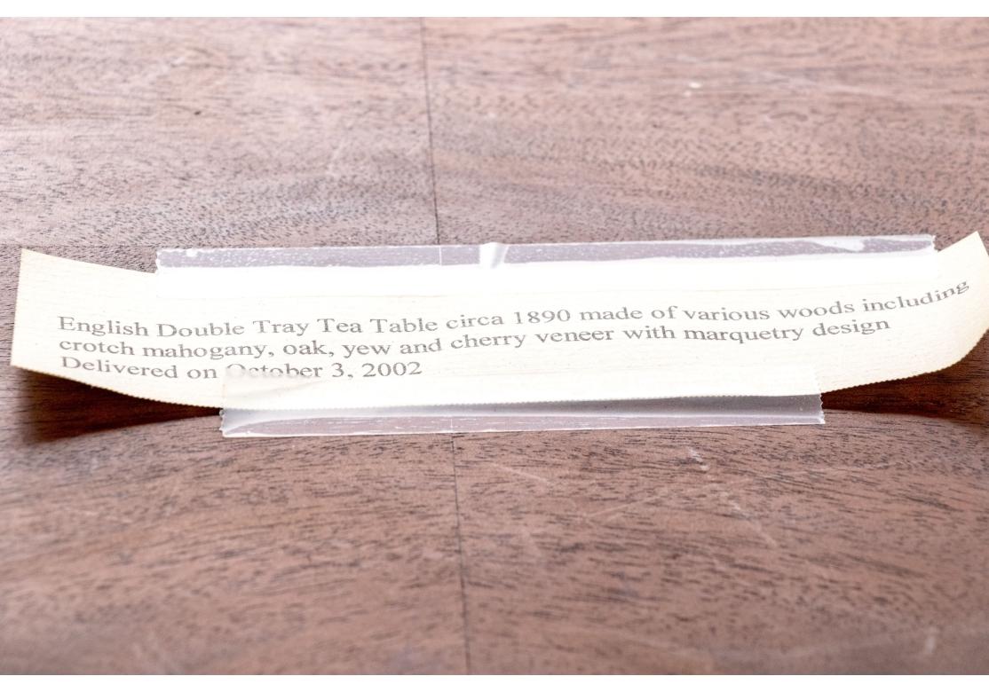 Une table à thé raffinée à double plateau en marqueterie ancienne, avec de riches placages de bois, dont l'acajou, le chêne, l'if et le cerisier. Plateau à bandes croisées en bois figuré et en bois satiné assorti à un livre, avec un médaillon