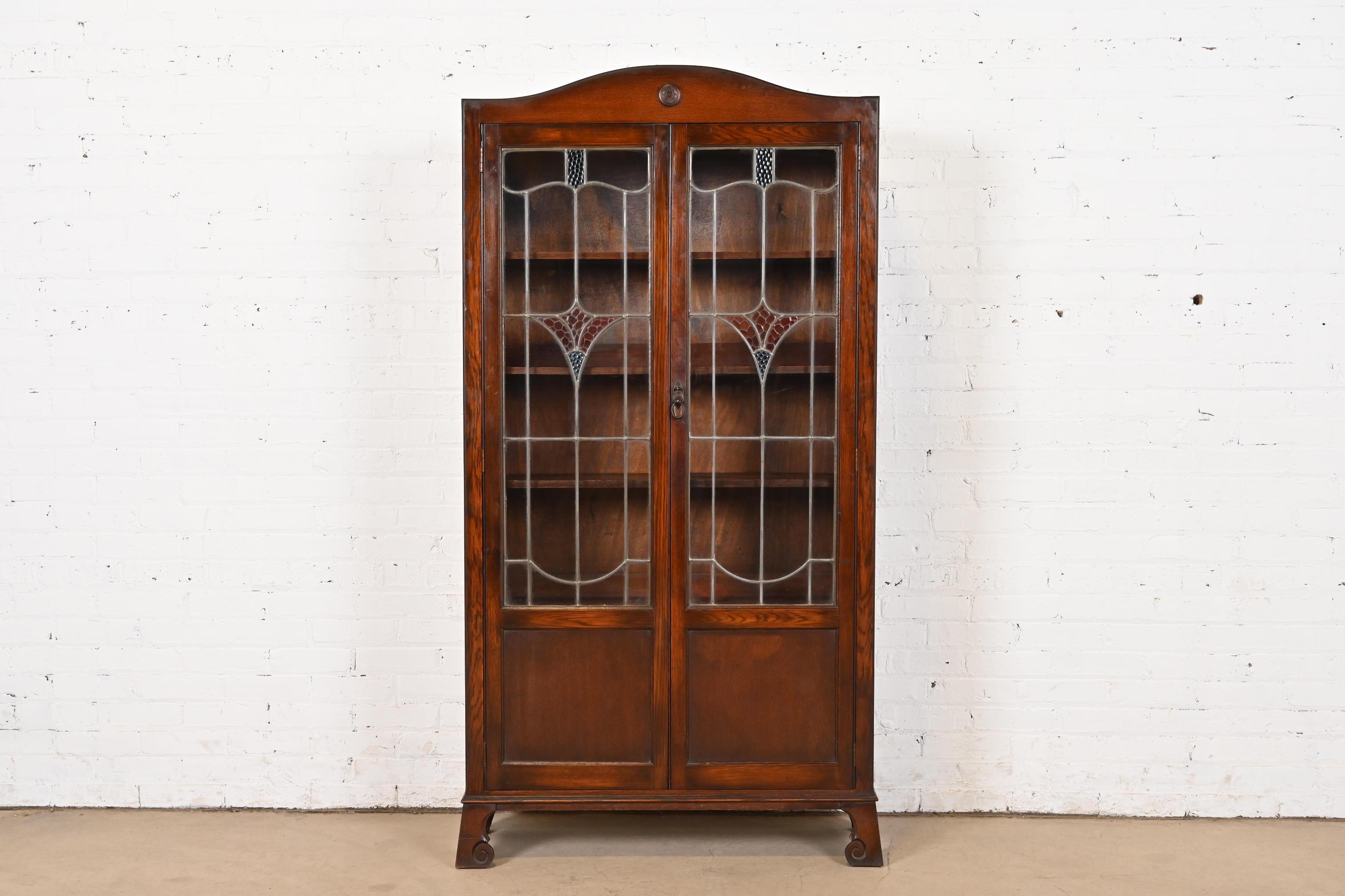 A gorgeous antique Mission, Arts & Crafts, or Late Victorian bookcase cabinet

In the manner of Charles P. Limbert Co.

By Eddershaws Furniture

England, Circa 1920s

Carved oak, with stained leaded glass doors, and original brass hardware. Cabinet