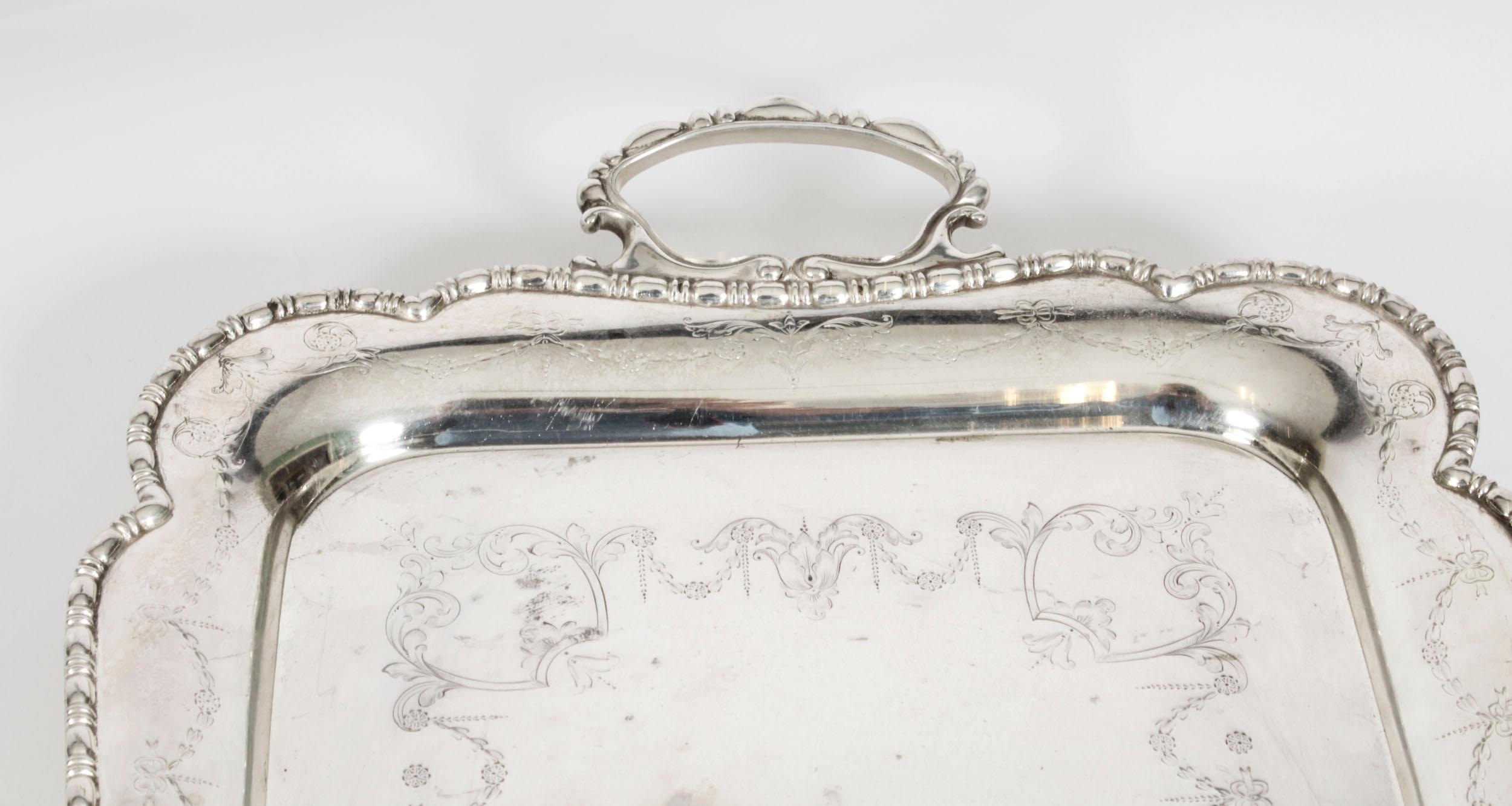 This is a superb antique English neoclassical silver plated tray by the renowned English silversmith, James Deakin, circa 1870 in date.
 
This rectangular tray features a deep set, decorative gadrooned border with elegant handles decorated with