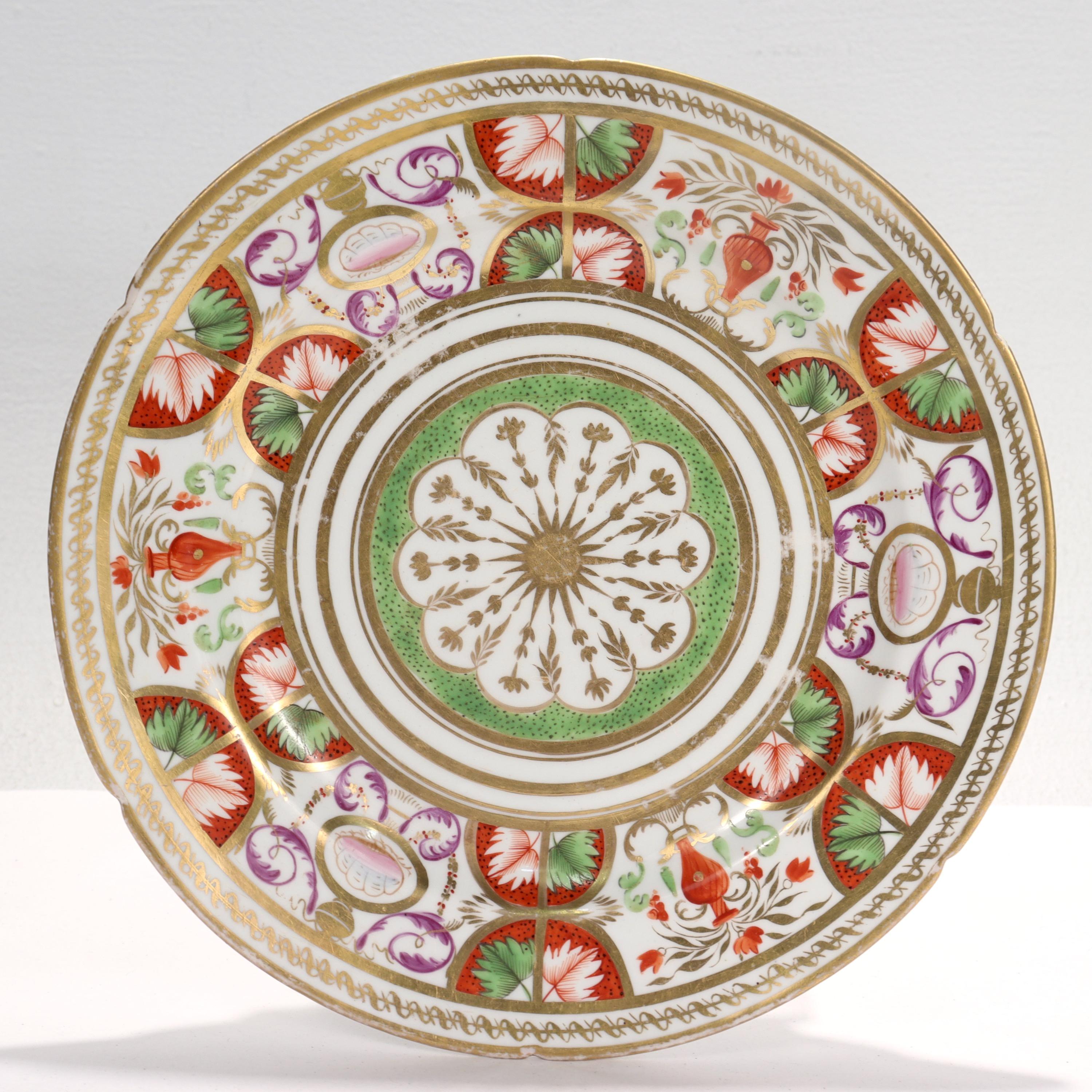 A fine antique English Neoclassical porcelain plate

Attributed to Coalport. 

Decorated throughout with rich gilding, and red, green, pink and purple floral devices.

With a shaped border.

Marked to the base with a gold sticker with