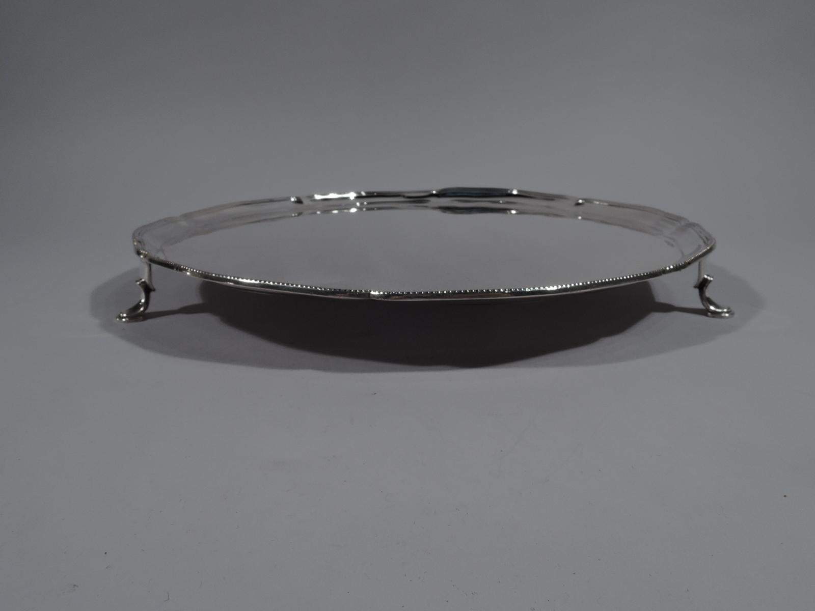George V sterling silver salver. Made by Lionel Alfred Crichton in London in 1930. Round with shallow lobes and beaded rim. Three hoof supports. An elegant serving piece in perennially popular neoclassical. Fully marked. Weight: 26 troy ounces.