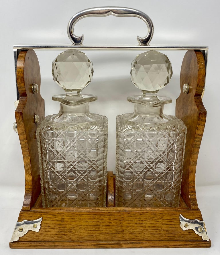 Antique English oak 2 bottle tantalus with silver-plate mounts and cut crystal decanters, circa 1880.