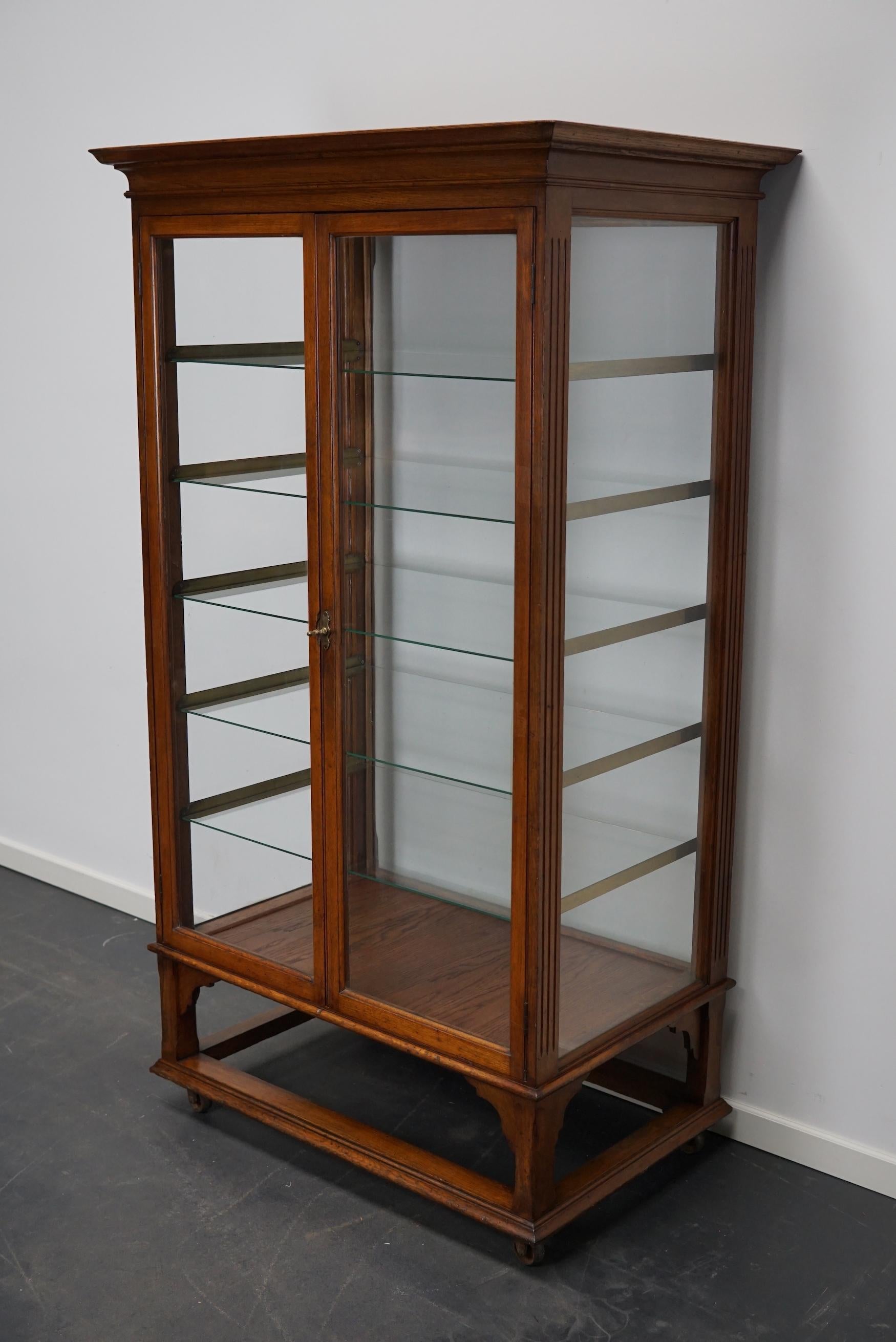 This very special antique oak bakery cabinet was made in the late 19th century. It was used to display and store pies in a bakery. It has two doors with a brass handle / lock, 5 glass shelves on brass shelve holders and glass all around. The vitrine