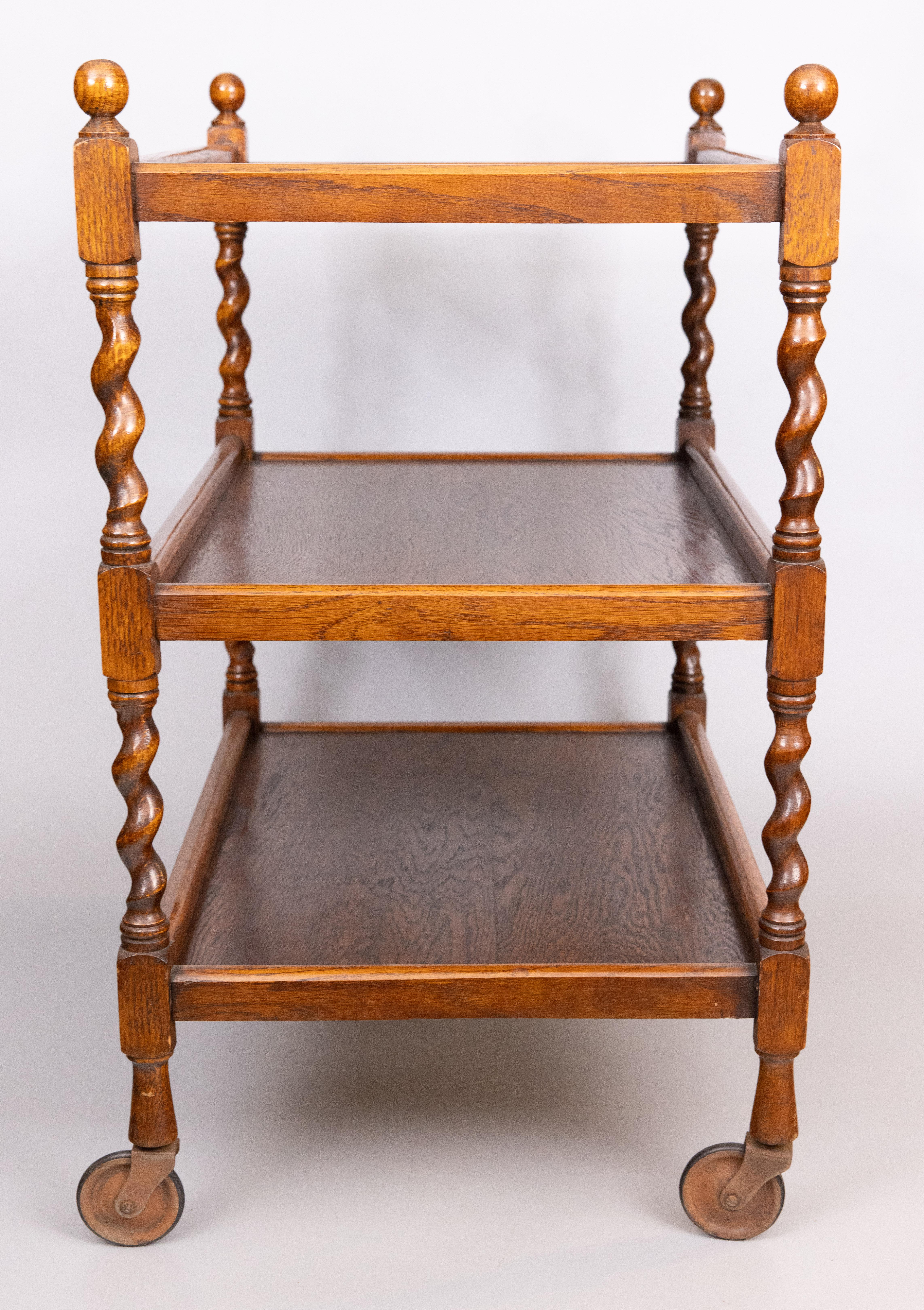 Classic antique English oak barley twist trolley cart with three tiers and original casters, circa 1920. Perfect for a beverage/bar cart or side table.
