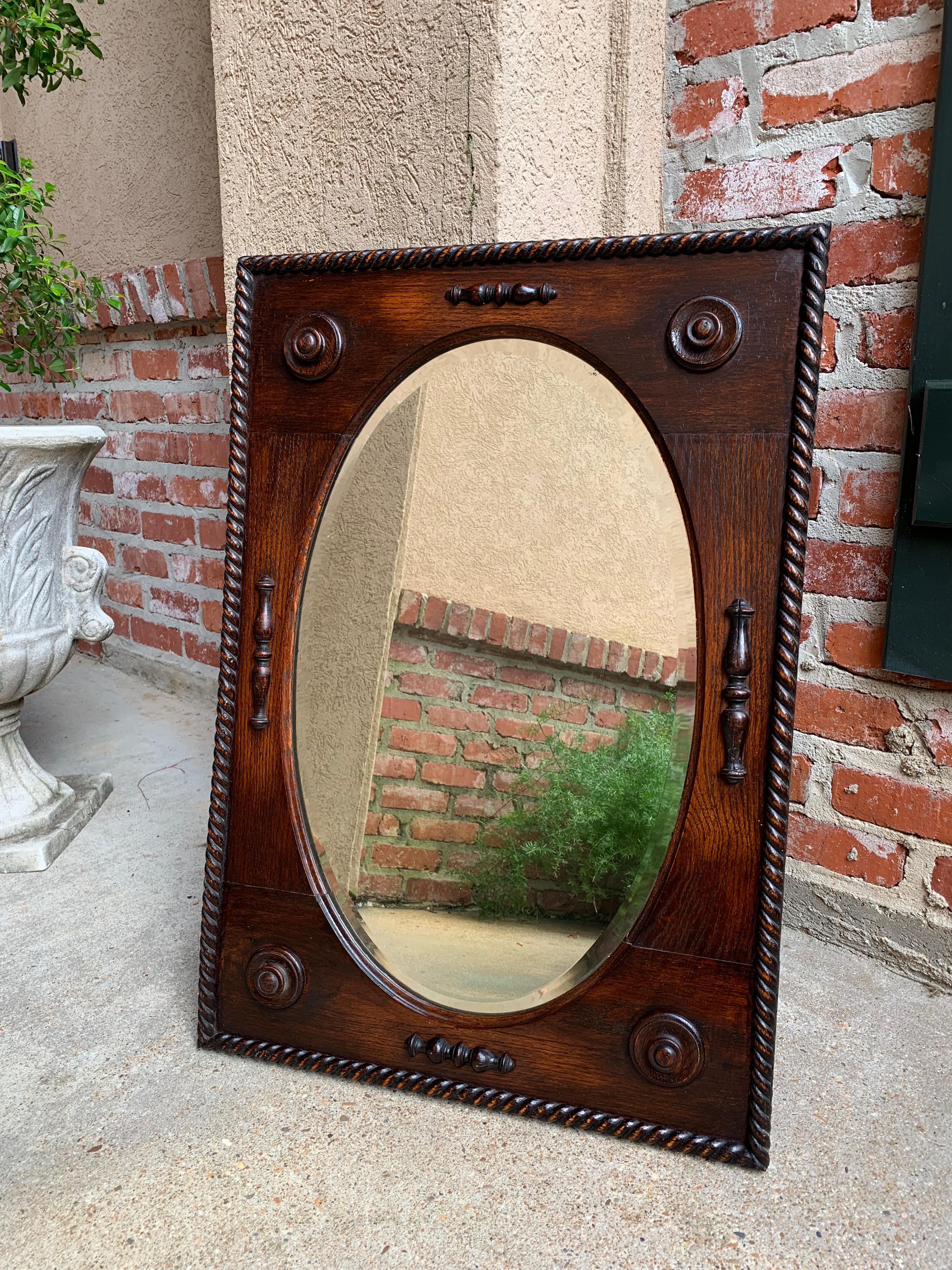 Direct from England, a lovely antique English oak frame wall mirror, with large rope or barley twist trim on the outer edges
~ Beveled inner oval edges and geometric buttons & applied trim on all the sides.
~ Overall quite a lovely mirror, with