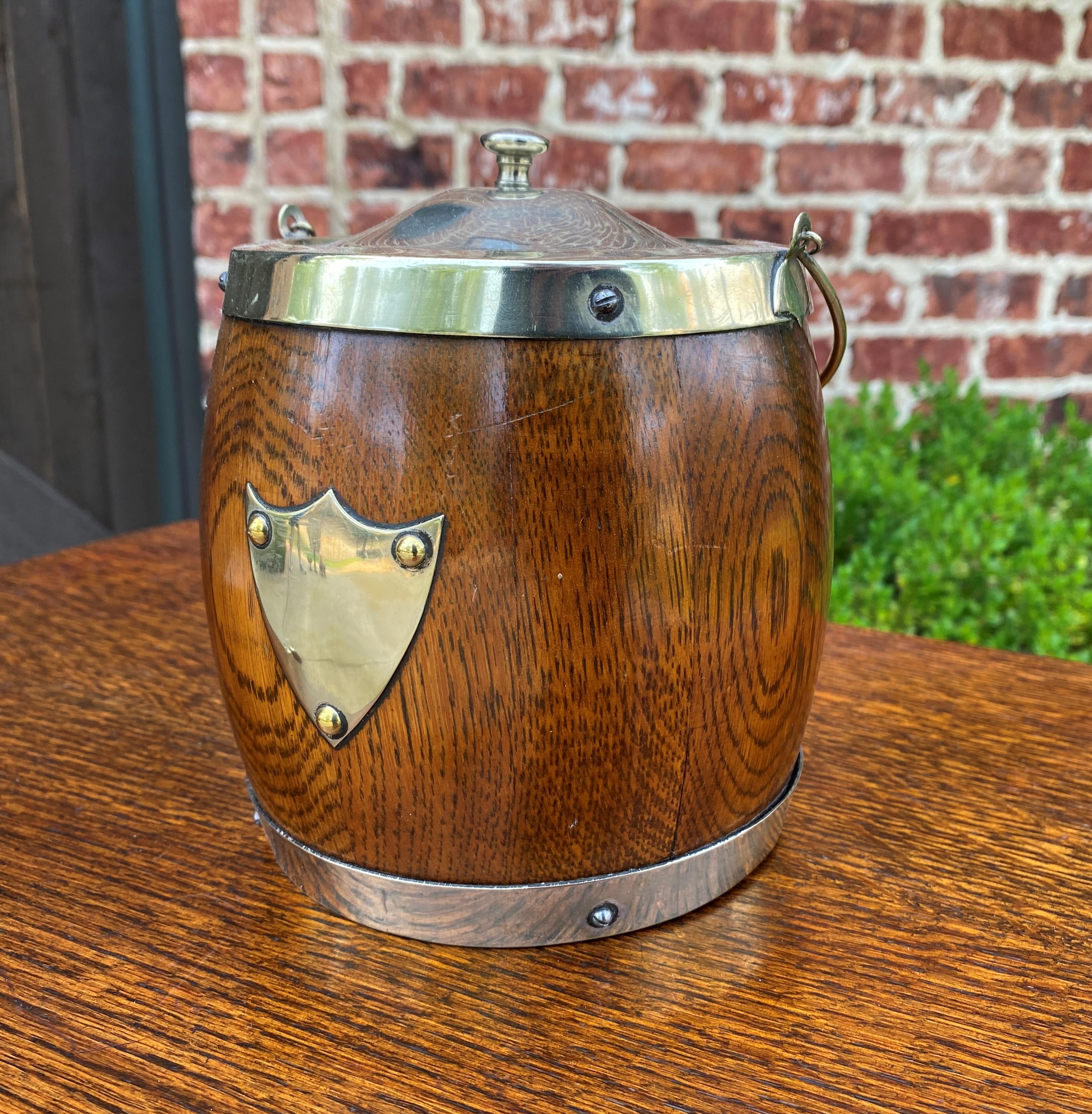 Charming Antique English oak biscuit barrel or tobacco jar with oak lid~~c. 1930s.

 Charming decorative accent piece for any room in today's home or office~~silverplate shield and lid~~interior porcelain lining.

Measures: 9.5