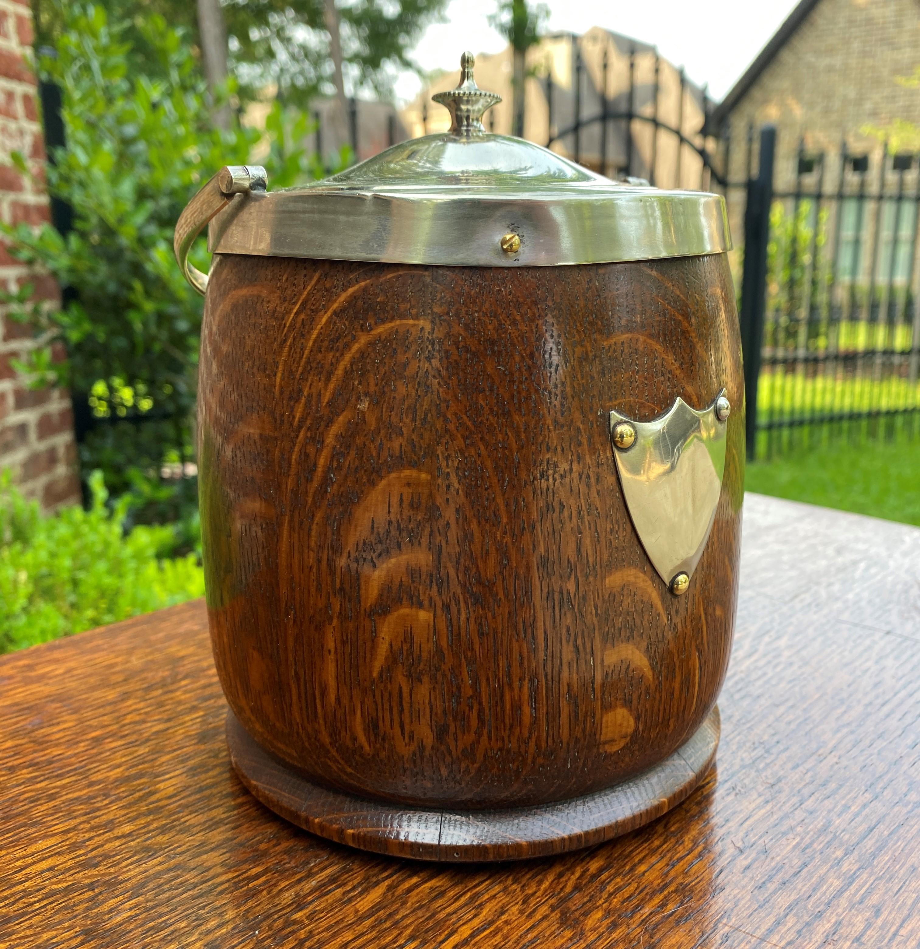 Charming antique English oak biscuit barrel or tobacco jar with oak lid~~c. 1930s

Charming decorative accent piece for any room in today's home or office~~silverplate shield and lid~~interior porcelain lining

9.5