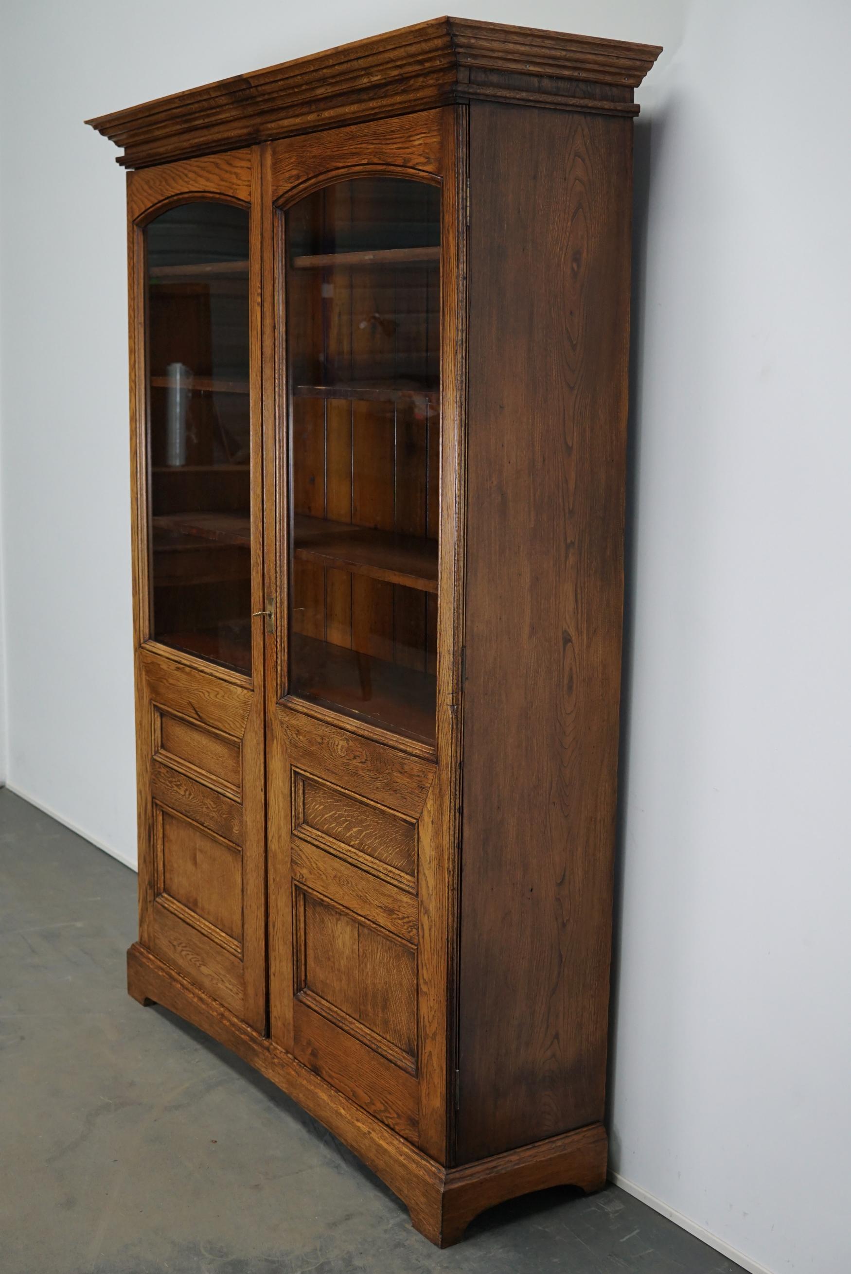 This bookcase was made from oak circa 1870s in England. It features two doors with a nice original key and lock. It remains in an amazing restored antique condition. The oak and six pine shelves / back on the inside have retained a beautiful patina