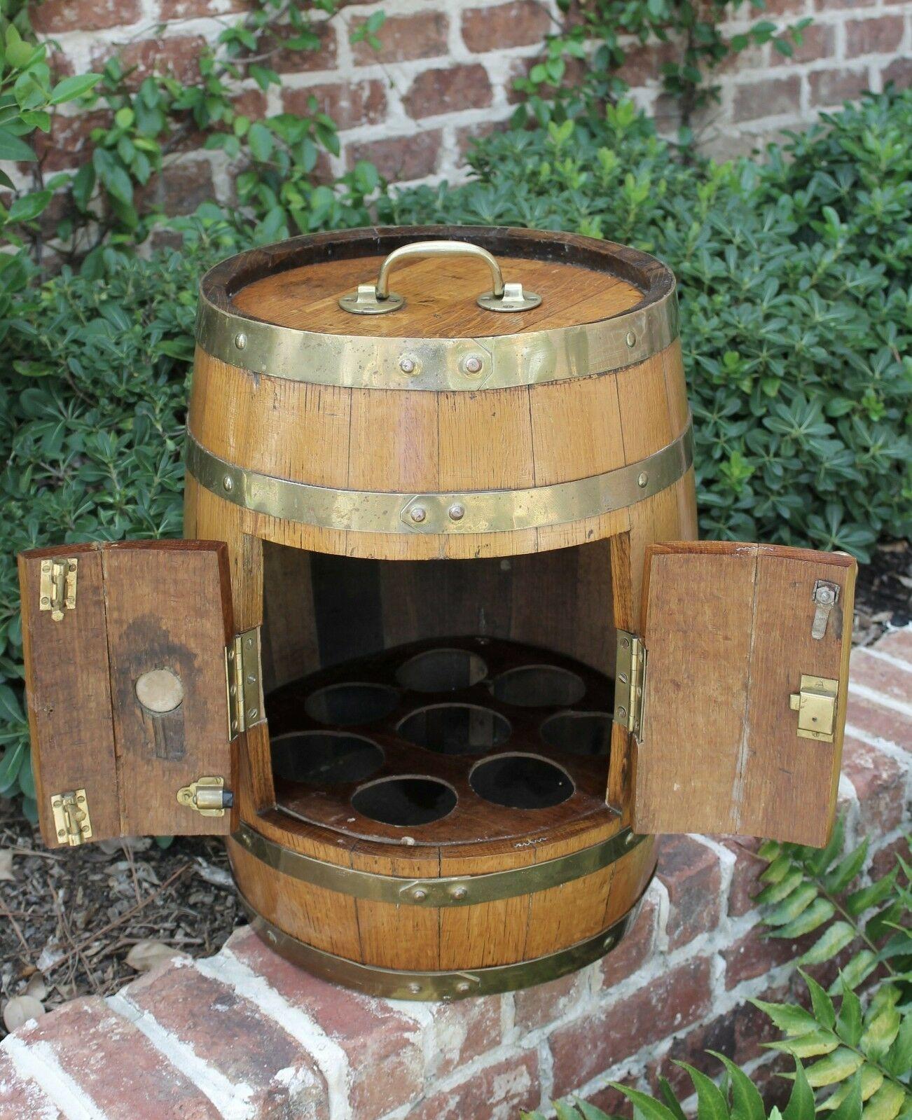 Unique antique English oak brass banded barrel wine or liquor bar cabinet pub decanter~~c. 1920s

Sturdy oak barrel with brass banding and hinged doors~~
Interior bar with cutouts holds 8 bottles~~
Round oak serving tray can be placed over lid