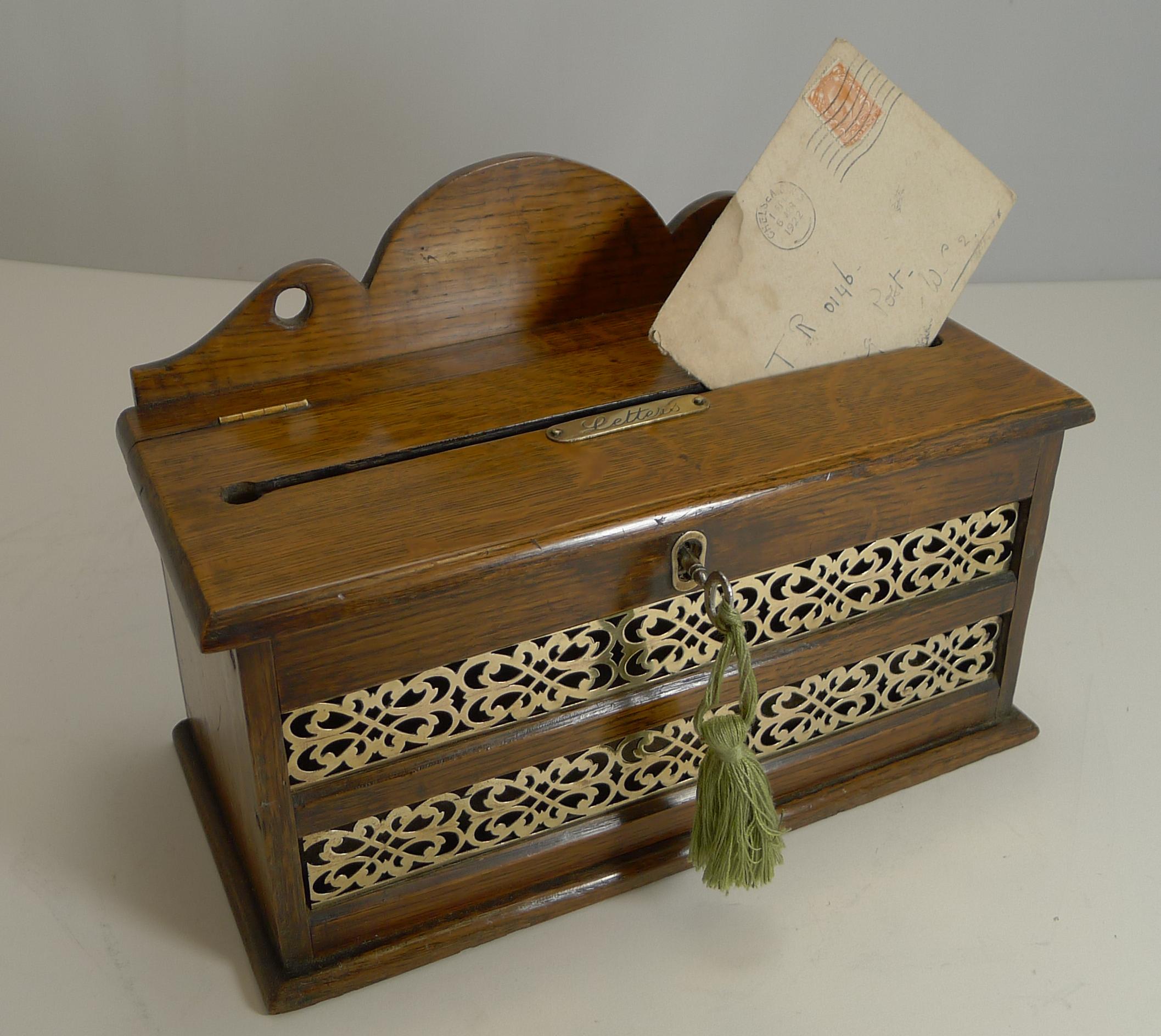 An unusual example, I have had many similar open at the top, but I have not had one of these as a closed box with a hinged lid.

Made from solid English oak, the front has a fretted brass panel allowing one to see if there were any letters