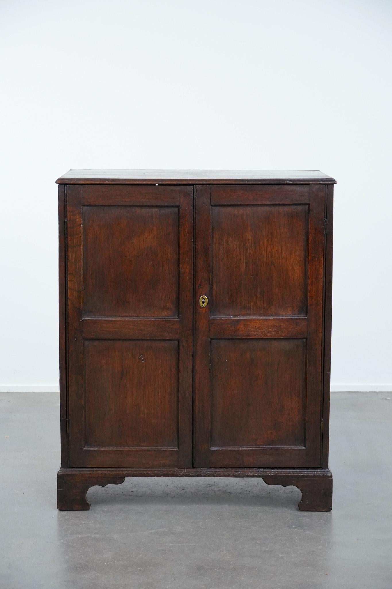 This charming English antique oak cabinet from the early 19th century is a beautiful, timeless addition to almost any interior. It is ideal for use in, for example, the hallway, living room, or bedroom. The cabinet features two doors and two shelves