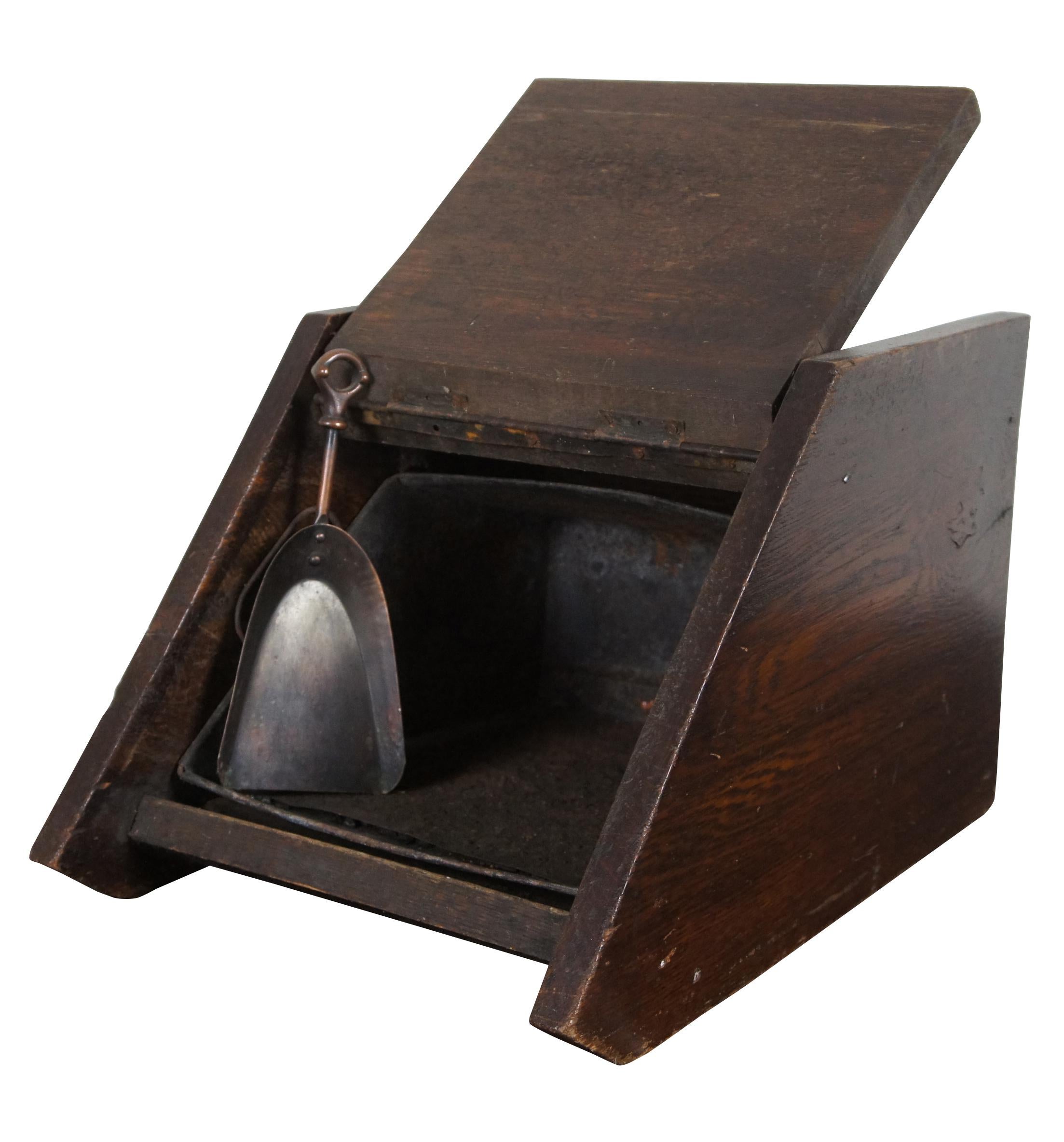 Antique English oak coal bin featuring a removable metal liner, top handle, and a copper scoop stored on the back.
 
