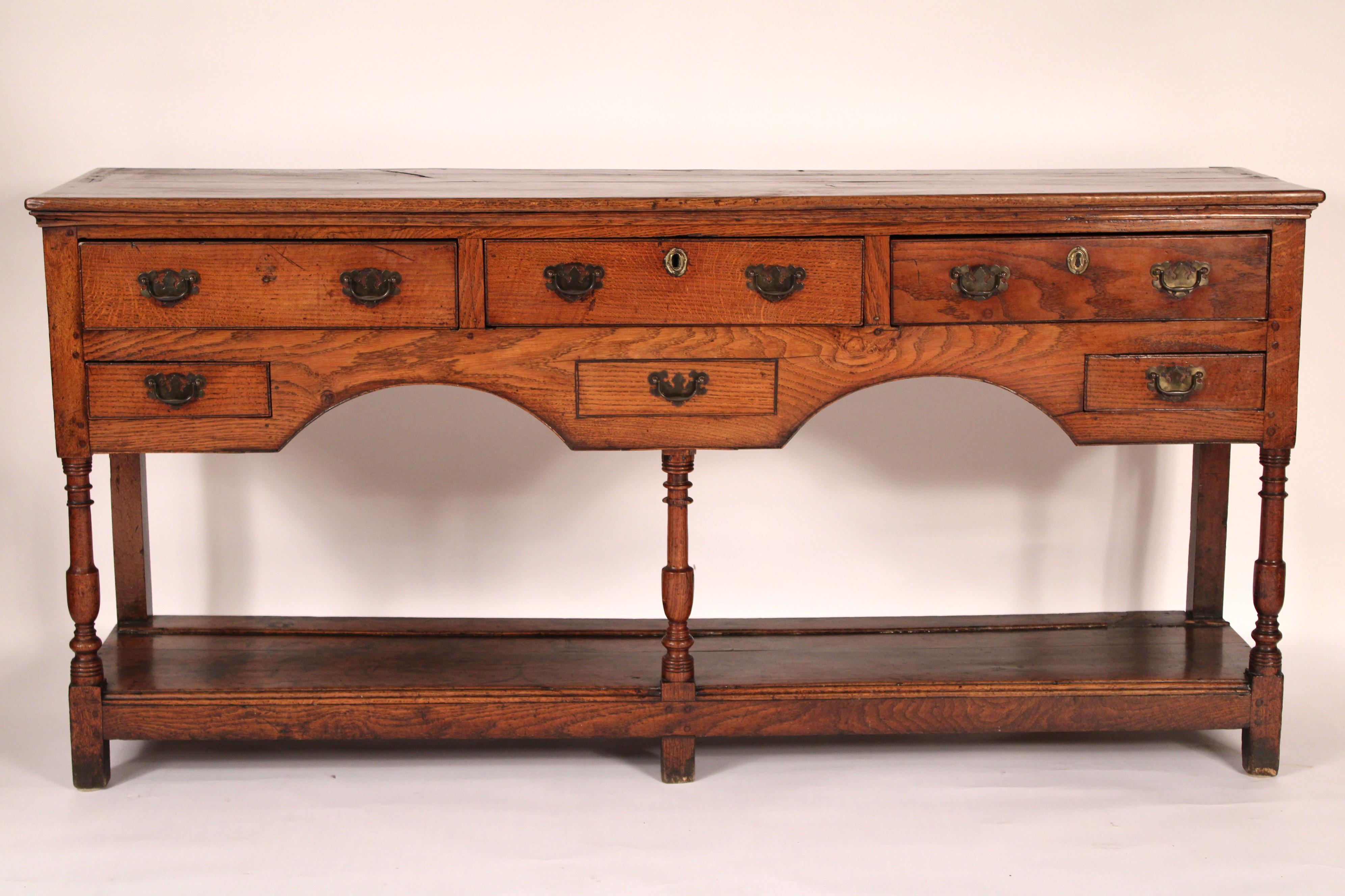 Antico comò inglese in Oak, inizio XIX secolo. Con un piano rettangolare a due assi con bordi frontali e laterali arrotondati,
3 cassetti superiori e due cassetti inferiori più piccoli, il cassetto centrale è fisso, gambe tornite a balaustro, un