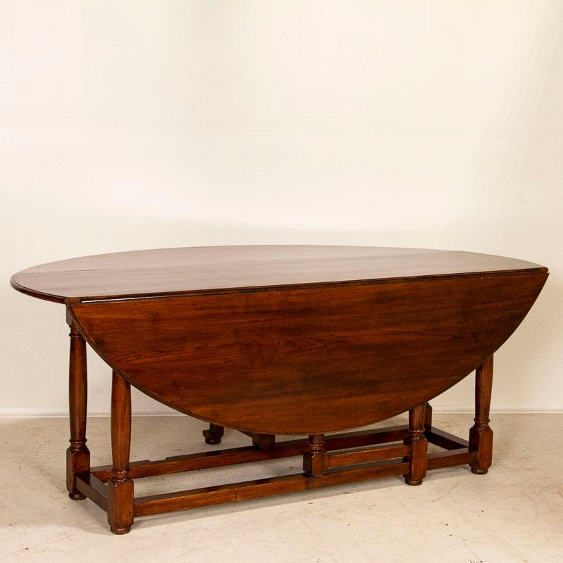 This striking gateleg dining table is also known as an English wake table with drop leaves. Notice the rick patina of the oak, aged and naturally distressed over generations of use and lovely turned legs. The large oval shaped top has 2 drop leaves,