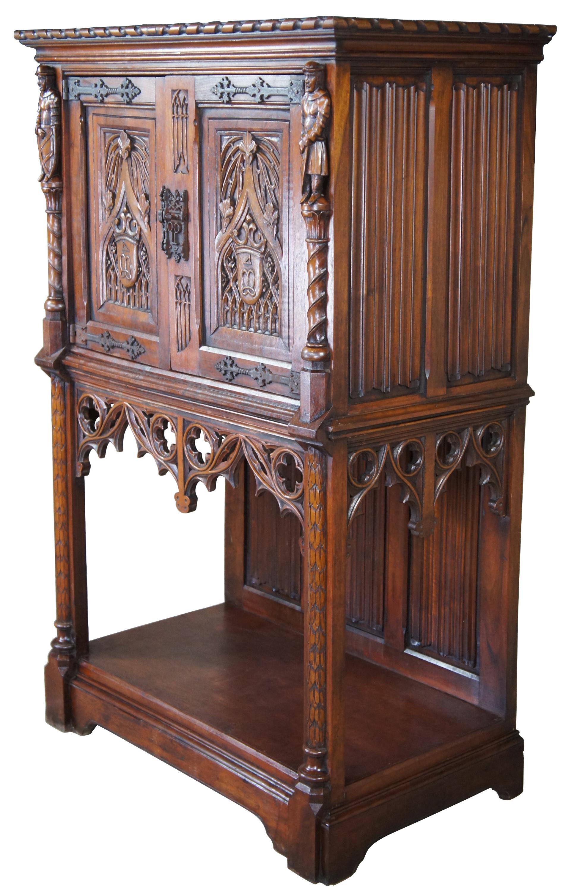 Antique English Gothic revival court cupboard or secretary desk, circa late 1800s. Made of Quartersawn Oak featuring figural columns, panelled siding and an arched pierced apron. The two doors are heavily detailed with an embowed design, crest and