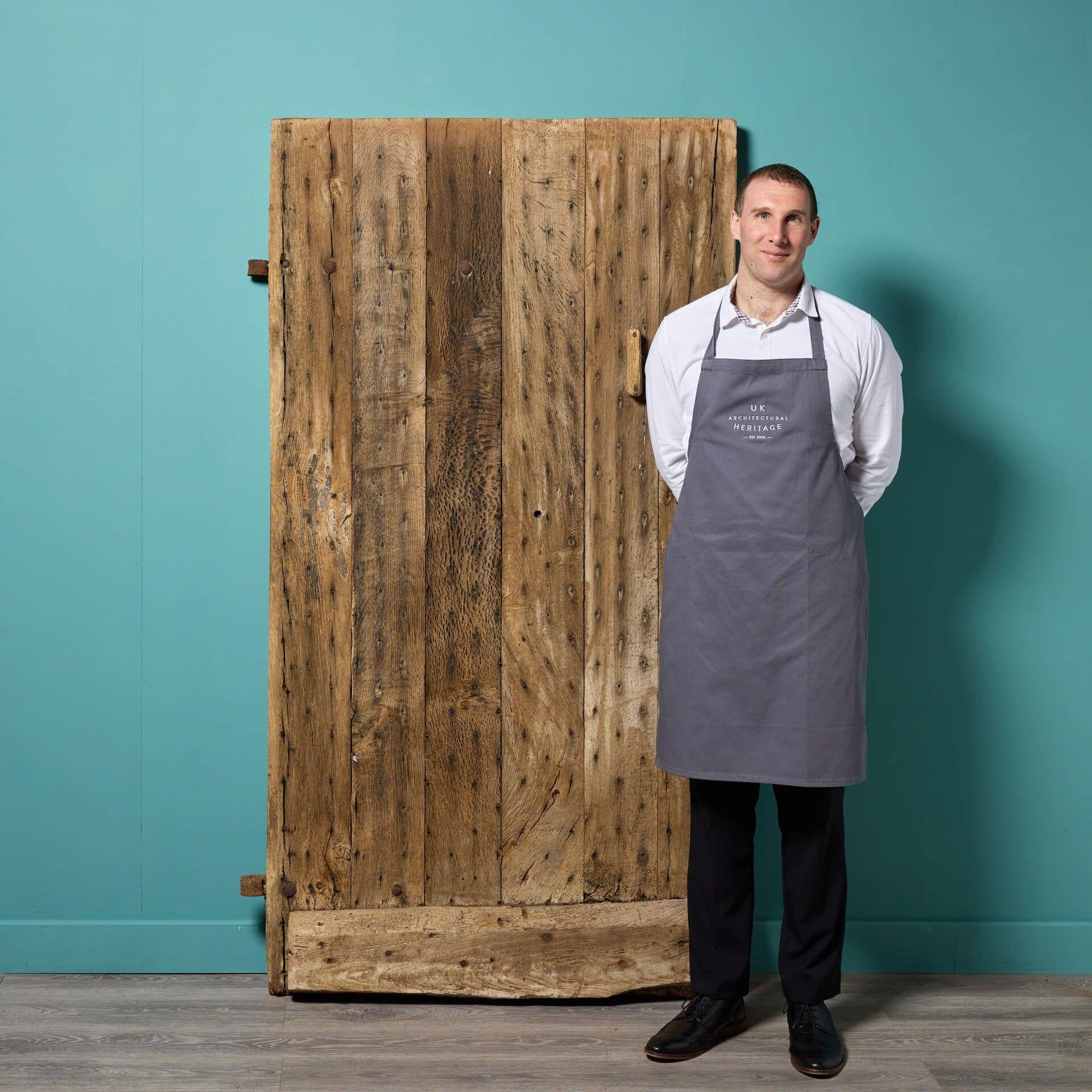 An antique English oak plank door dating back to the 1600s suitable for interior or exterior use. Brimming with character, this reclaimed door tells the story of 17th century craftsmanship. To one side, it is constructed using horizontal planks, the
