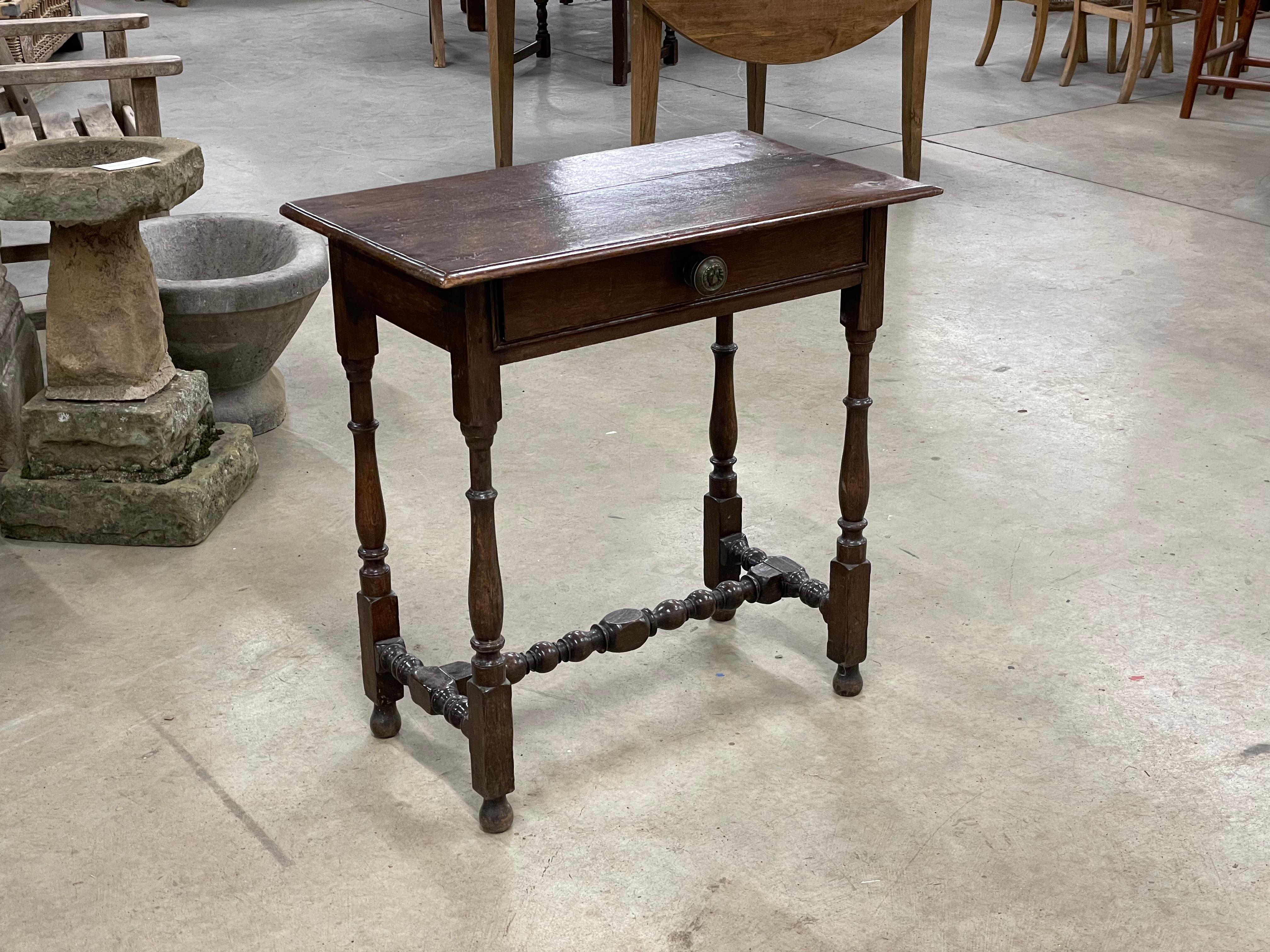 Lovely patinaed antique oak side table in the Charles II, 17th century style, It has a rectangular top and molded front and side edges, above a frieze drawer with an associated Regency metal handle with a repousse lion's mask on the front of the