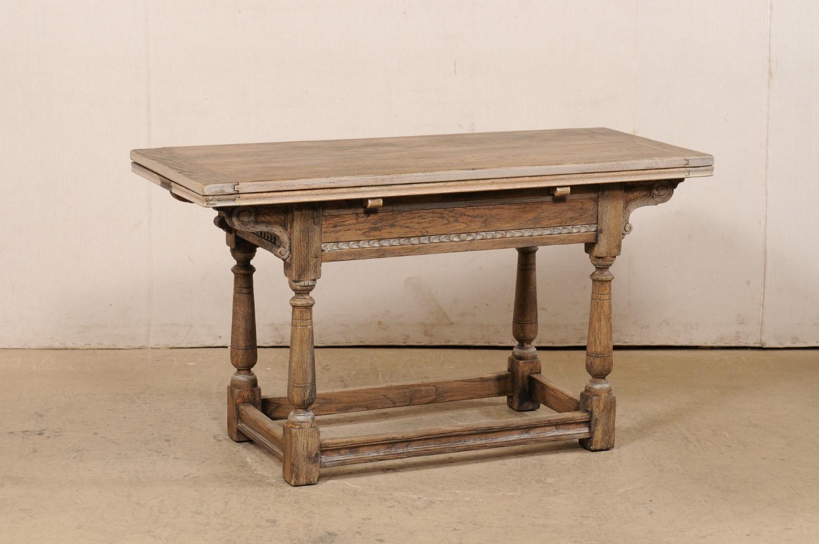 An English carved oak wood table, with expandable top, from the early 20th century. This antique table from England features a rectangular-shaped top (with two leaves tucked beneath which can be pulled out for a larger surface area when needed),