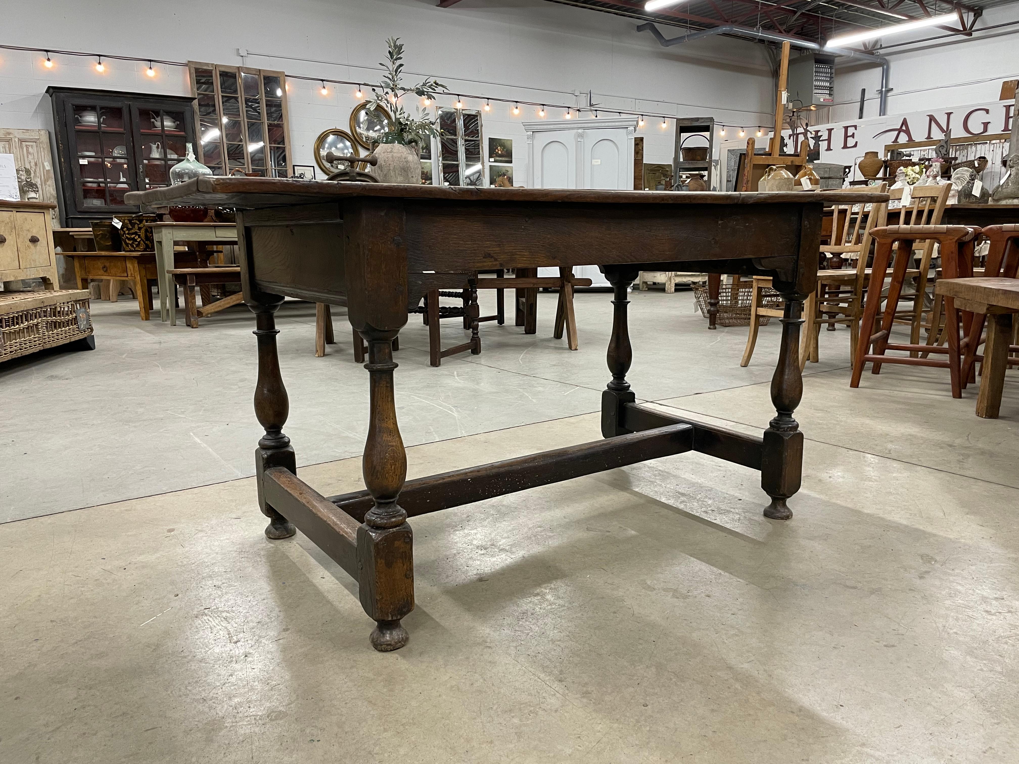 Antique English oak trestle table, with beautiful patina, in the Charles II 17th century style. It has a rectangular top above plain friezes. There are shaped brackets to the undersides at each end of the long sides. It sits on baluster turned legs