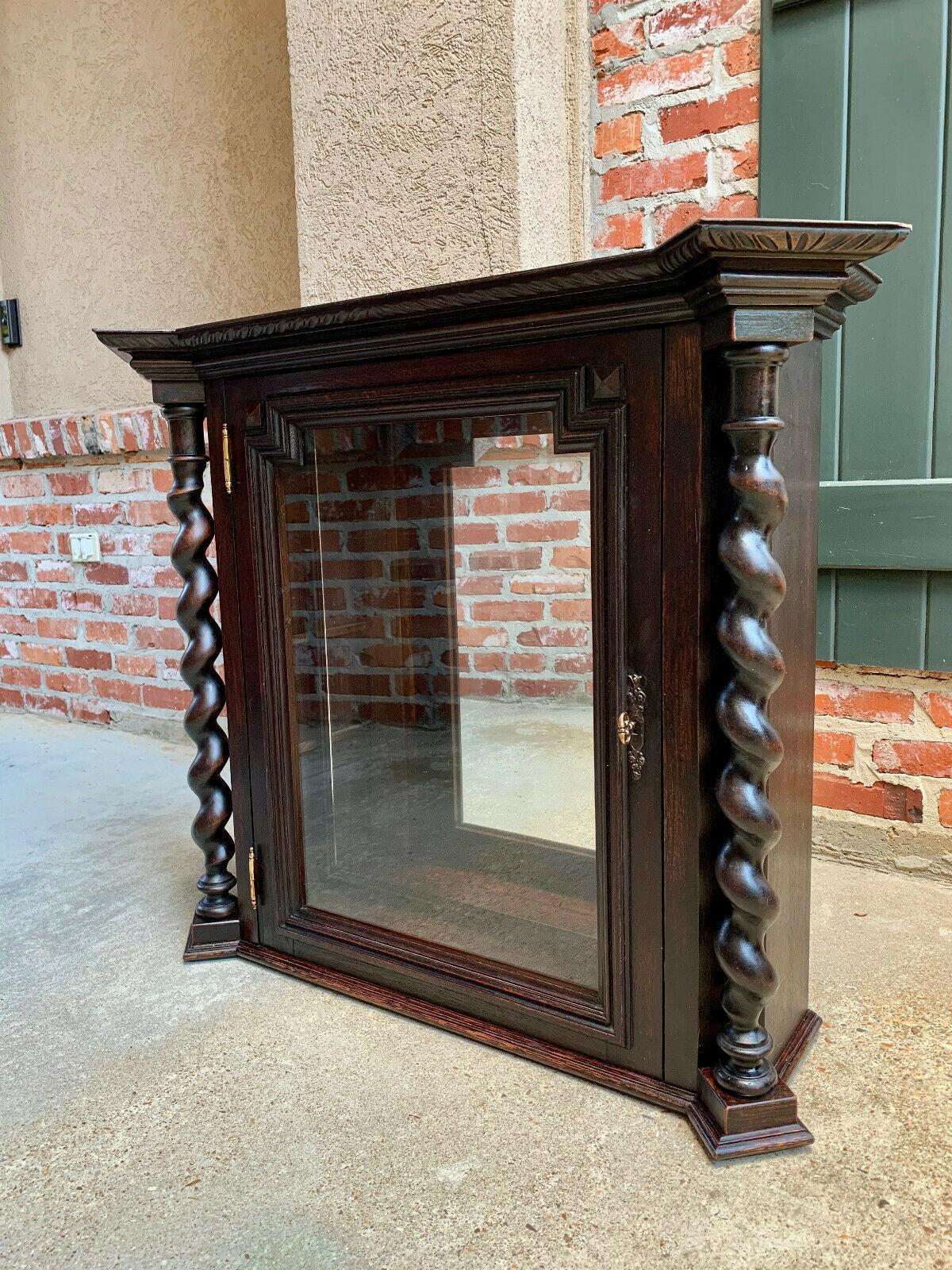 ~Direct from England~
A beautiful antique English wall cabinet or vitrine, large in size and unique in style!

Stepped out upper crown has carved beveled edges on all three sides, above the full length barley twist columns and the framed glass