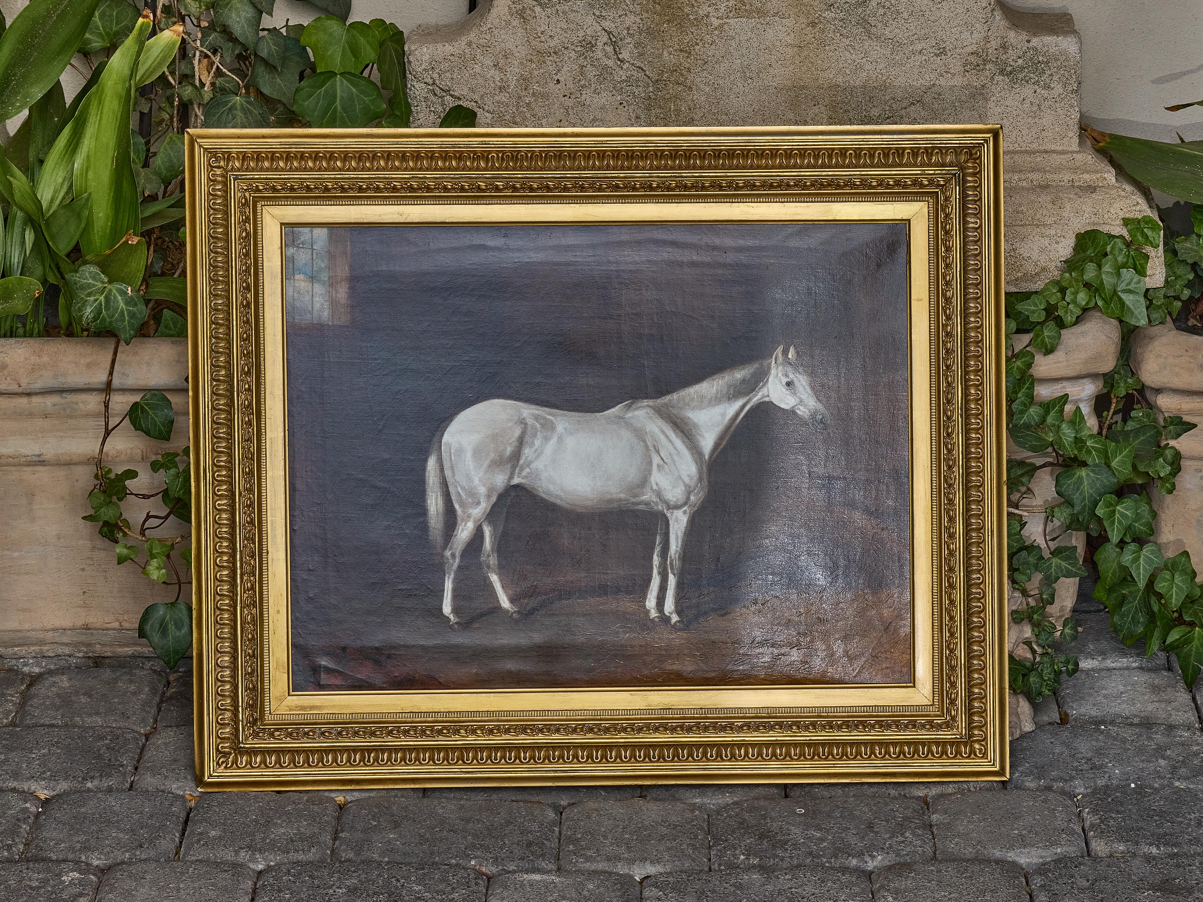This English oil on canvas painting, dated 1884, captures the quiet elegance of a white horse standing in a dimly lit stable interior. Painted with rich tonal contrasts and an eye for equine anatomy, the piece is a tribute to the 19th-century