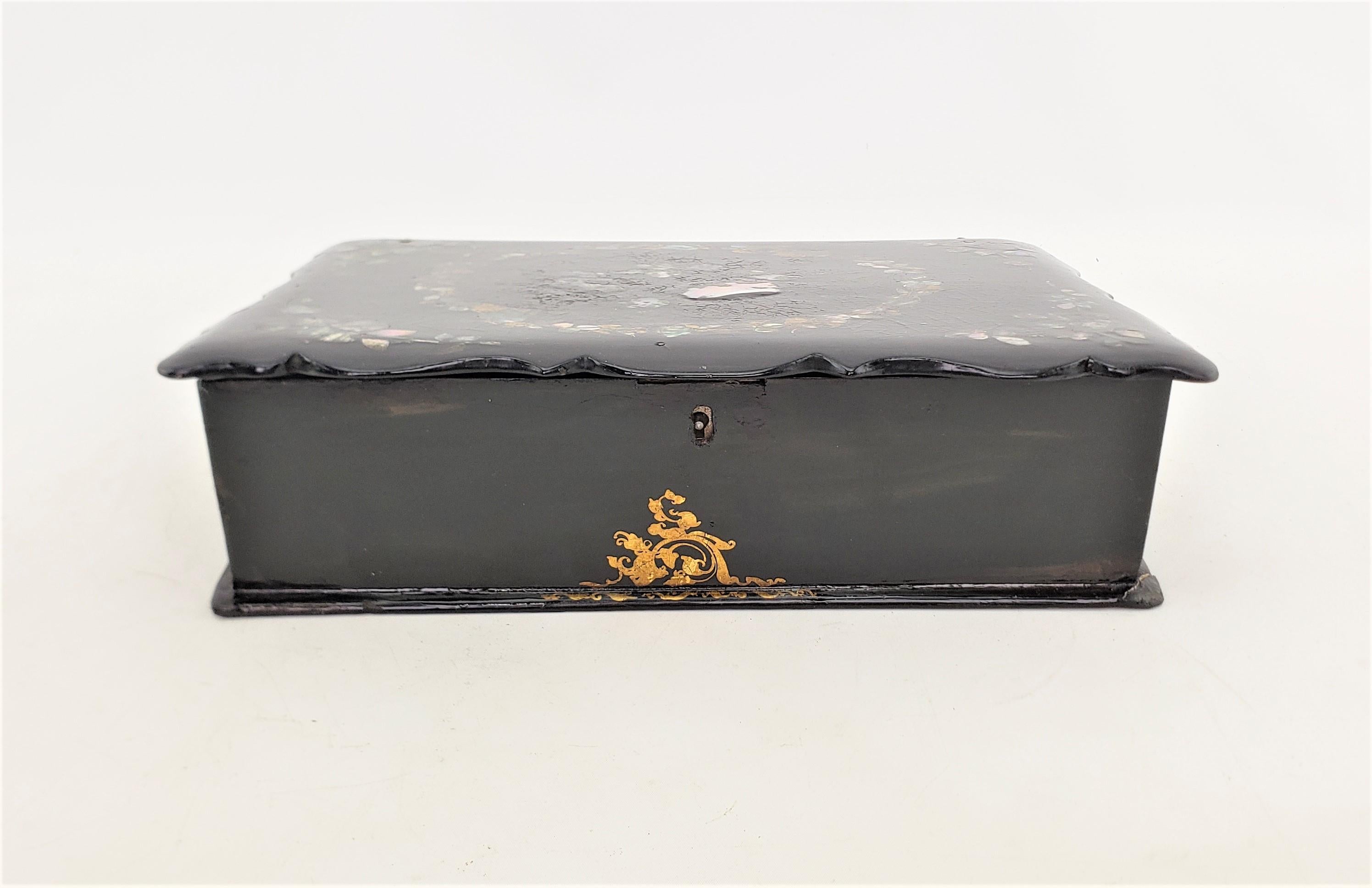 This antique writing box or lap desk is unsigned, but presumed to have originated from England and date to approximately 1880 and done in the period Victorian style. The box is constructed of paper mache which has been treated with a lacquer finish