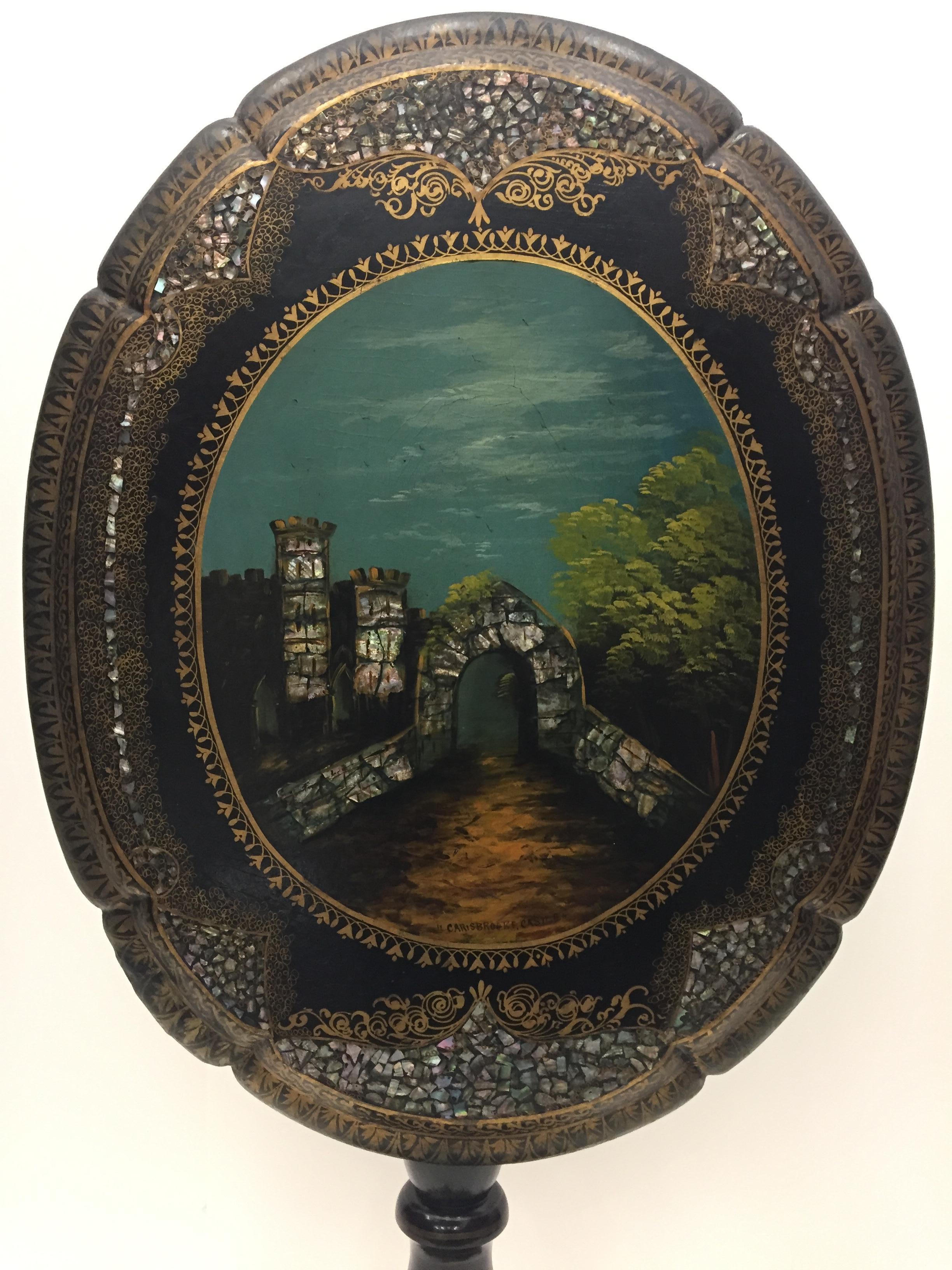 A true work of art in an oval tilt-top antique table having a hand painted scene of Carisbrooke castle and environs on the top with beautifully inlaid mother of pearl and other gold decorative material. The turned column is a beautiful shape, as is
