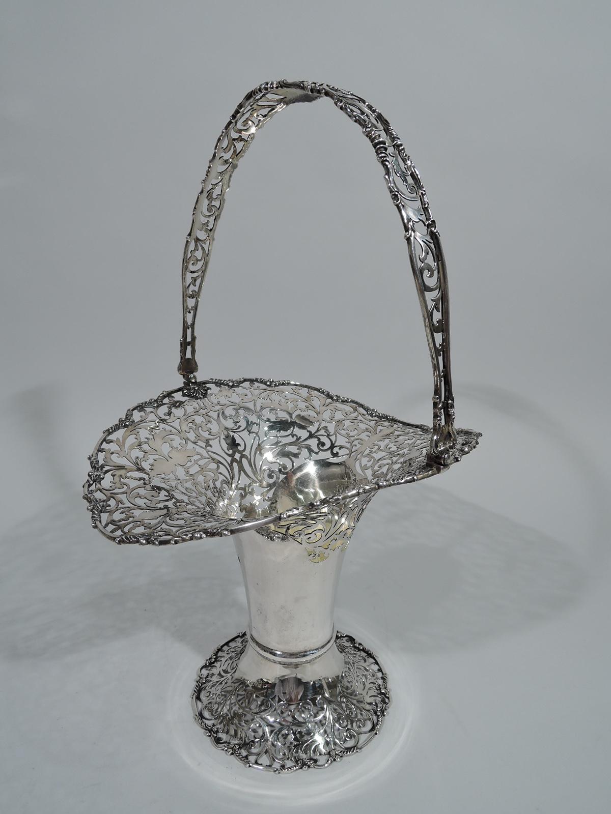 George V sterling silver basket. Made by David Landsborough Fullerton in Exeter in 1920. Cylindrical with base knop, raised and spread foot, everted rim, and swing handle. Rim, foot, and handle have pierced scrollwork and foliage. London hallmark.