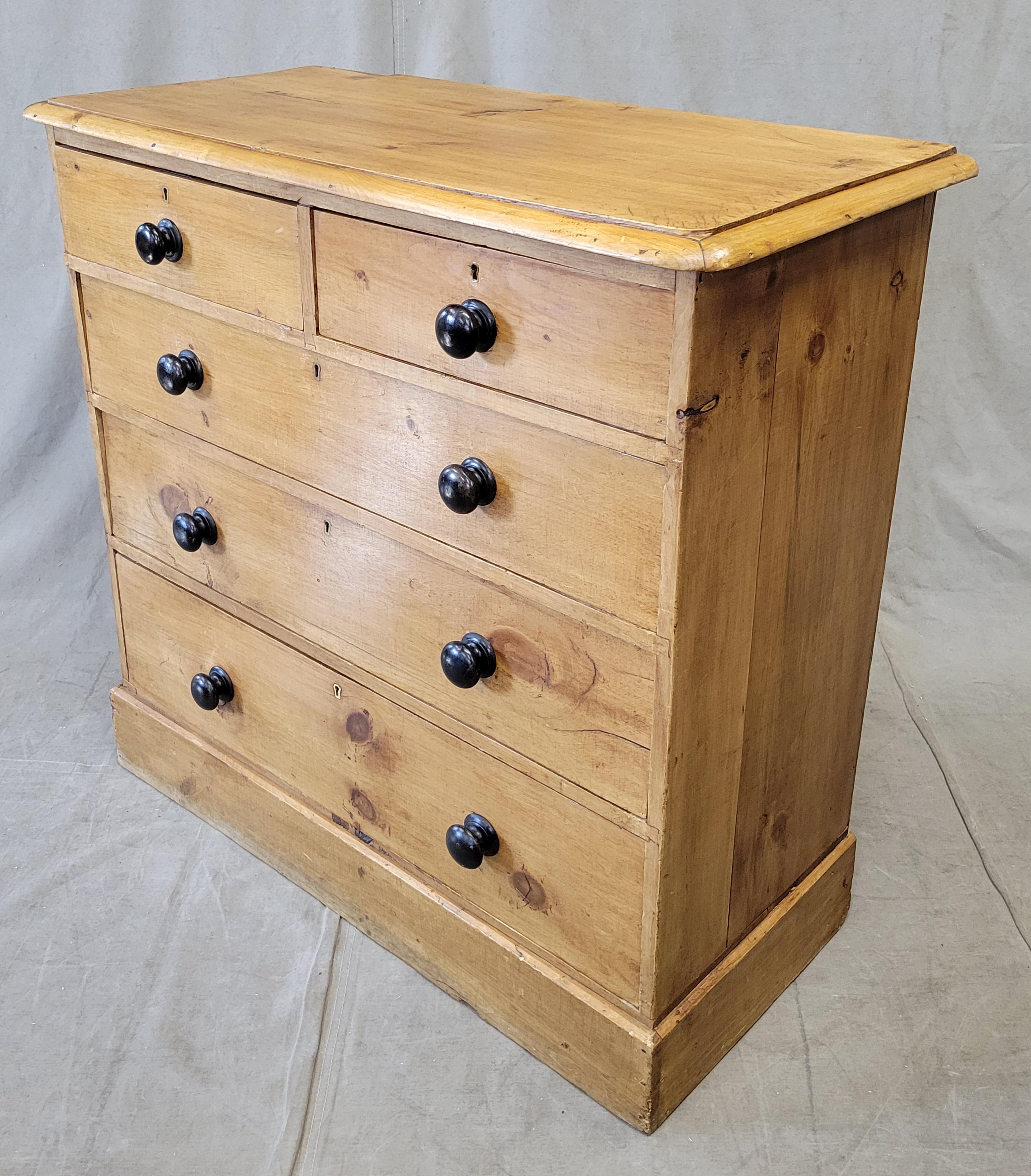 A classically beautiful antique circa 1900 English pine chest of drawers dresser. The old pine has a beautiful glow and the dark wood knobs provide contrast and visual interest. Old locks and brass keyholes are intact however there is no working